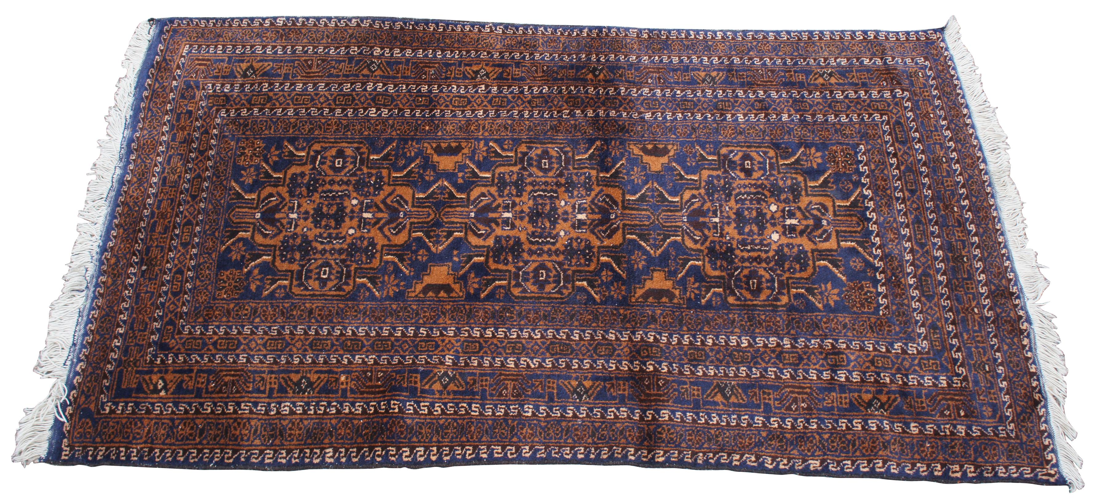 Vintage Persian Baluch wool area rug. Features a geometric repeating pattern with a field of navy blue accented with orange / brown, and tans. Baluchi rug, Baluchi also spelled Baloochi or Balochi, floor covering woven by the Baloch people living in