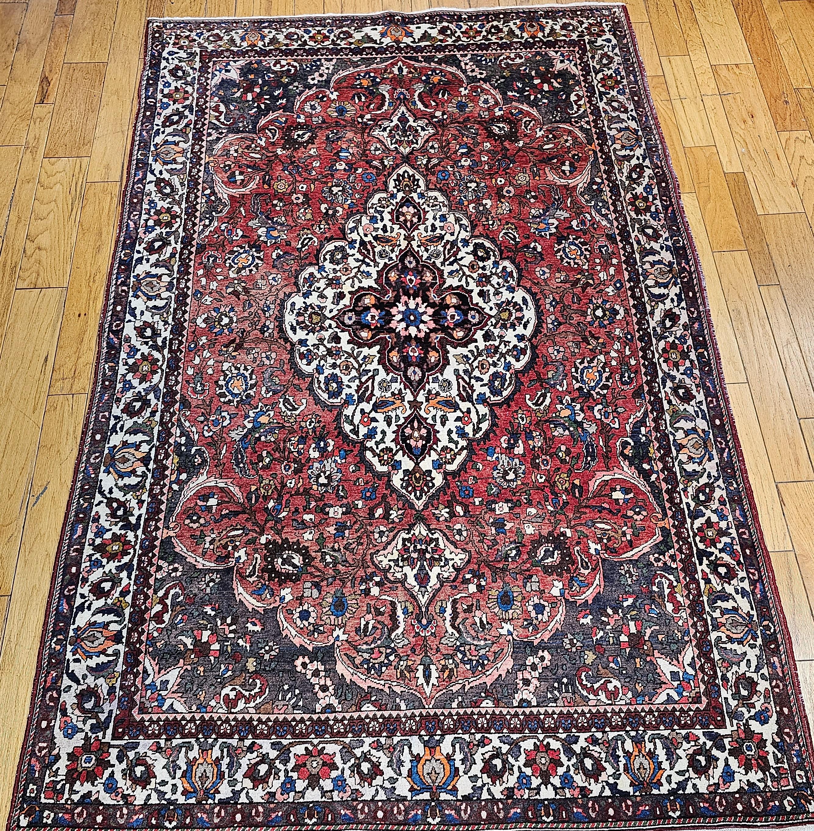 Room-size Persian Bakhtiari tribal rug from the Western Persia in a medallion floral pattern from the mid 1900s. A large central medallion is in a cream background color. Bakhtiari rugs are renowned for their beautiful floral designs and the use of