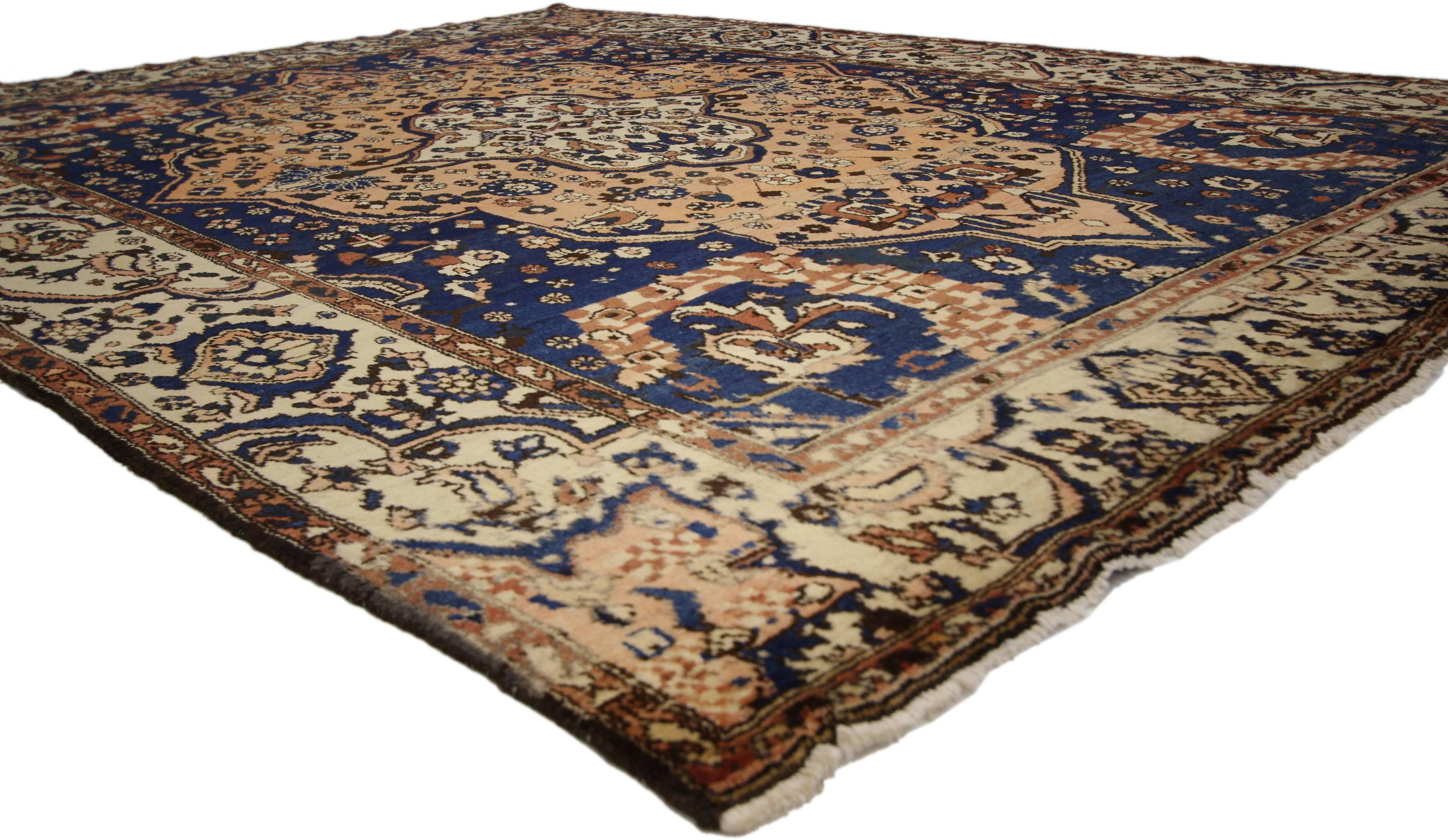 75714 Vintage Persian Bakhtiari Rug with Rustic Modern Italian Style 07’05 x 09’05. With its navy blue and warm rustic peach hues, this hand knotted Persian Bakhtiari rug is well-balanced and poised to impress. It features a concentric cusped almond