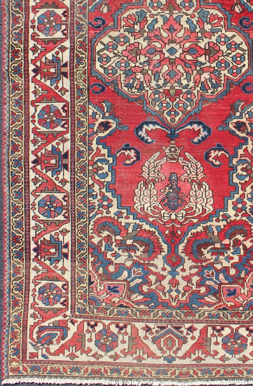 Persischer Bachtiari-Teppich im Vintage-Stil mit kunstvollem Zentralmedaillon und sattem Rot-Blau.
Dieser mehrfarbige persische Bakhtiari-Teppich aus der Mitte des 20. Jahrhunderts aus dem Iran hat einen roten Hintergrund und ein zentrales