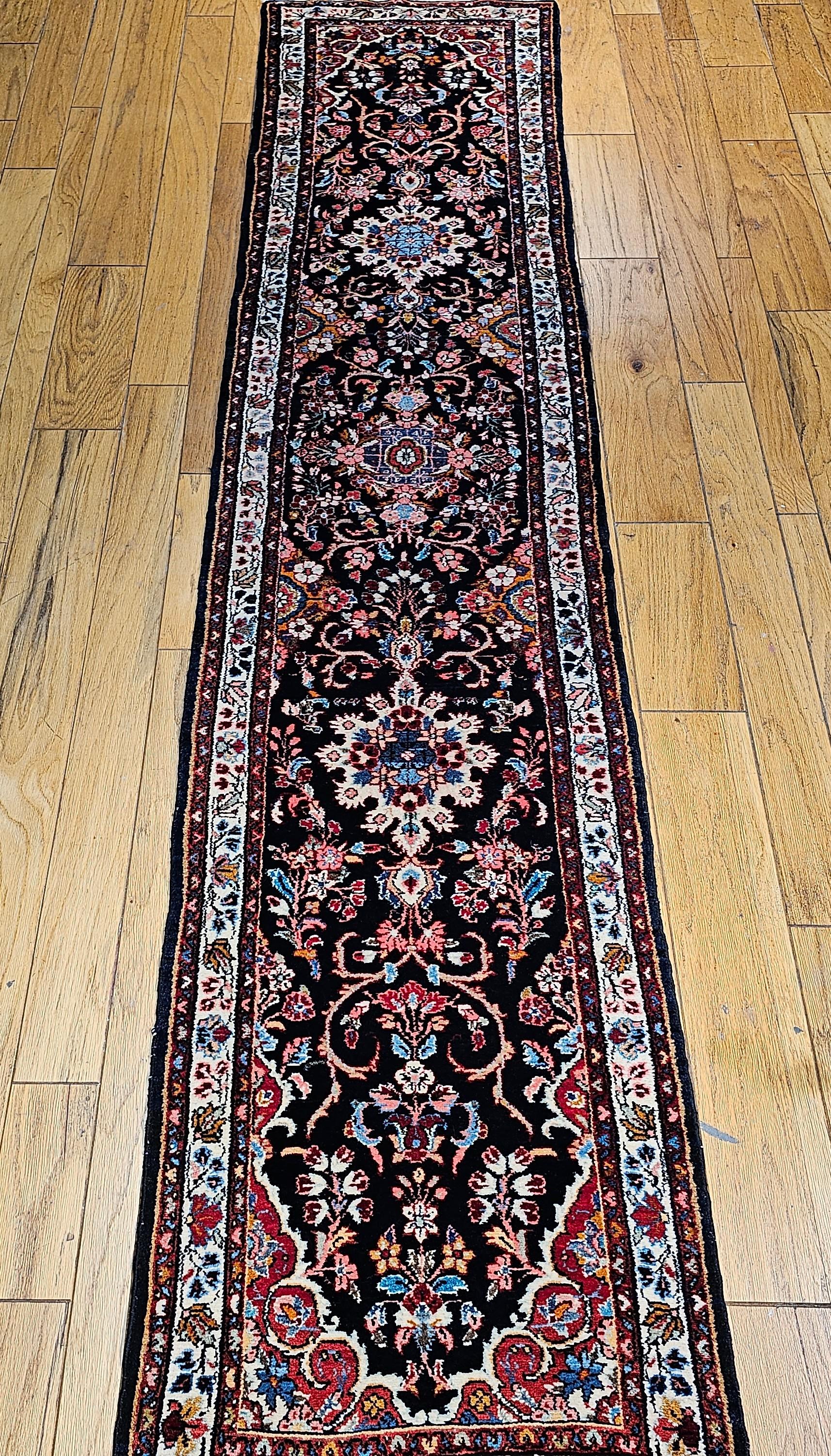Vintage Persianl Bakhtiari Stammes-Läufer in einem floralen Design aus der Mitte der 1900er Jahre.  Der Läufer hat ein florales Design mit einem  Serie von Blumensträußen und Medaillons in einem marineblauen Farbfeld mit floralen Mustern in Blau,