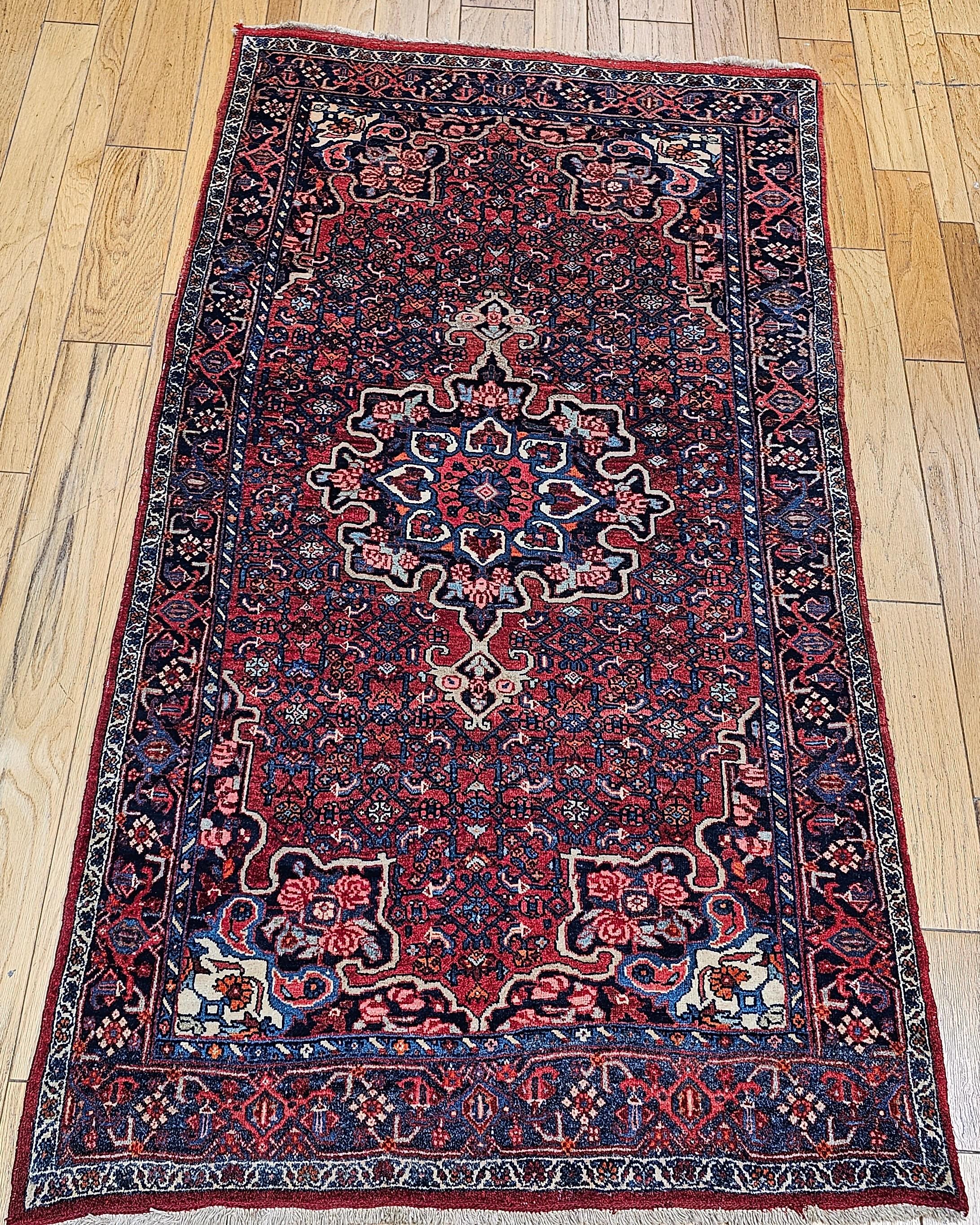 Vintage Persian Bidar area or gallery rug in a medallion floral pattern from the early 1900s.  The carpet has a central medallion and anchor pendants rendered in blues, reds, ivory, and pink with a dark gold outline.  The corners have four rose