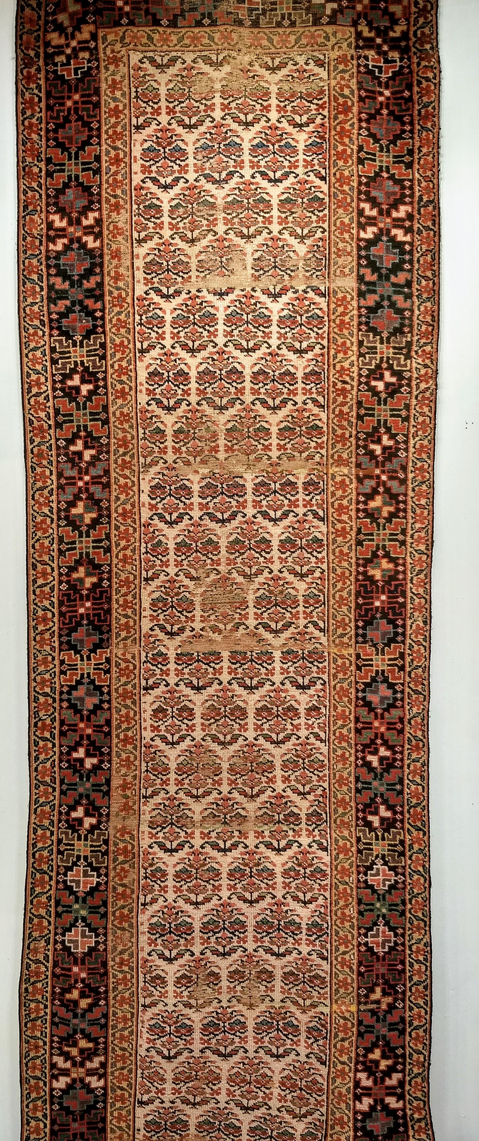 Cette ancienne coulisse persane Bidjar, tissée dans le quatrième quart du XIXe siècle, est une pièce d'art textile rare et très recherchée. Son champ ivoire, caractéristique rare et convoitée, est orné de têtes florales stylisées, interprétées comme