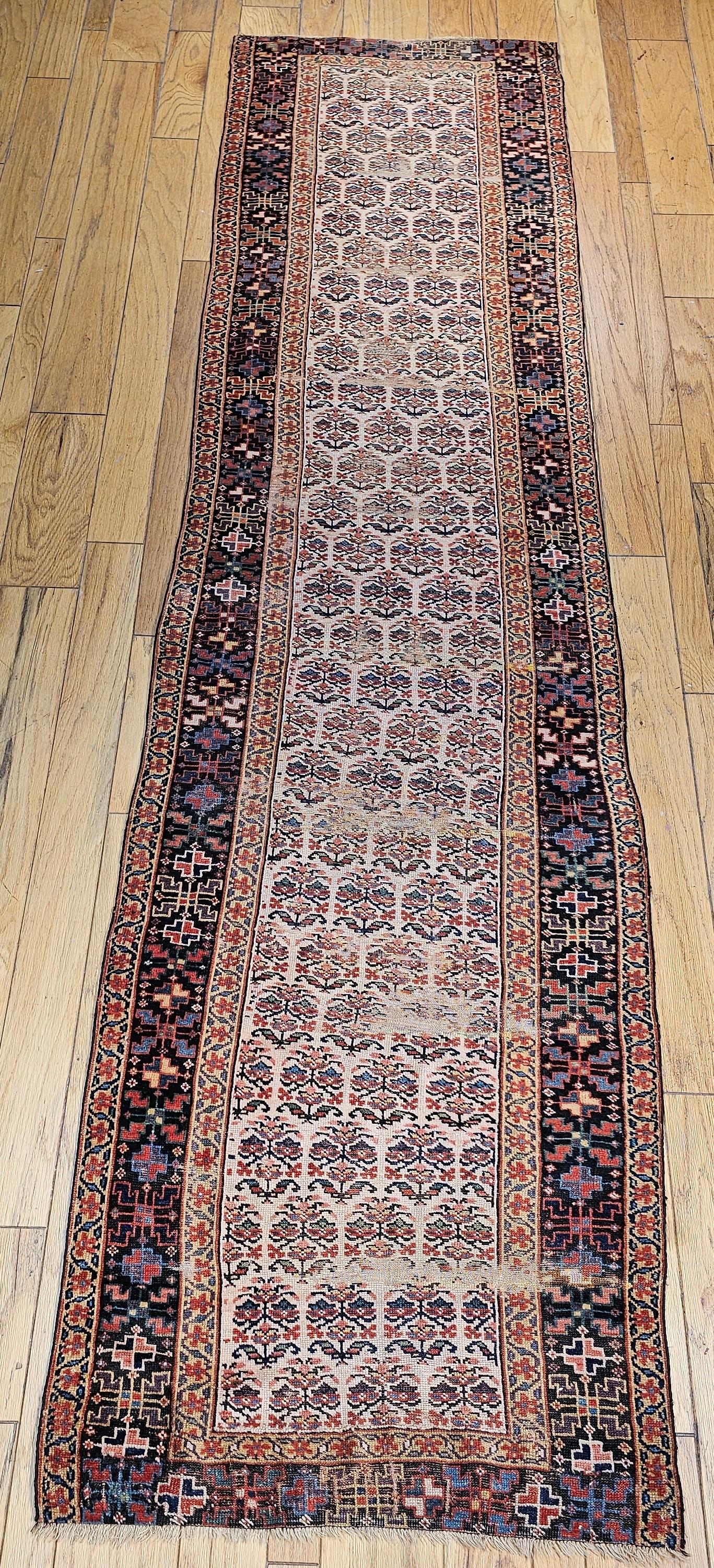 Vintage Persian Bidjar runner circa the 4th quarter of the 19th century. The field is in ivory which is extremely desirable with flower heads which is considered a variation of the paisley pattern. The major border is in navy background with