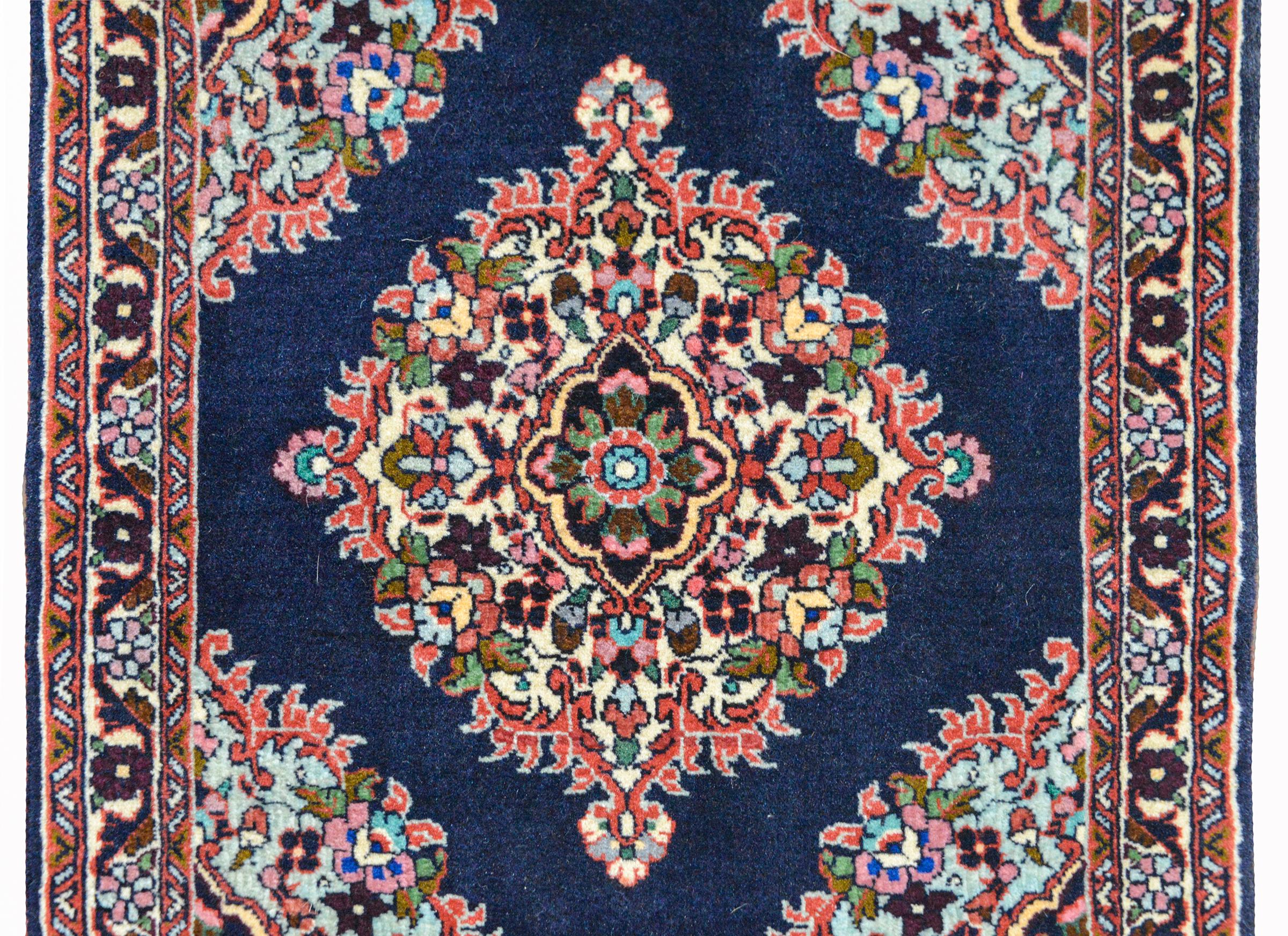 A wonderful vintage Persian Bidjar rug with a diamond floral medallion woven in red, pink, green, yellow, and light indigo against solid dark indigo background, and surrounded by a floral and scrolling vine patterned border.