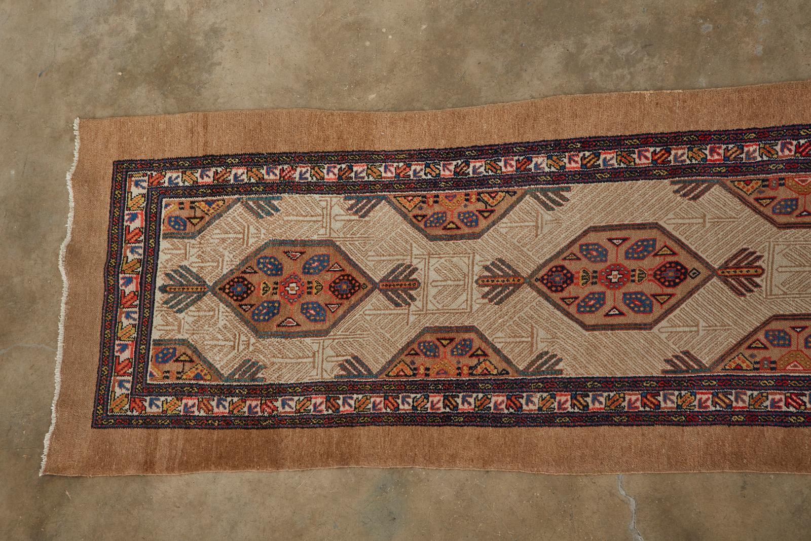 Long vintage Persian camel hair Sarab hallway runner over 20 feet in length. Features a traditional tribal style design with six cartouche shaped medallions over a cream colored center field. Handwoven with soft camel hair colored with natural dyes.