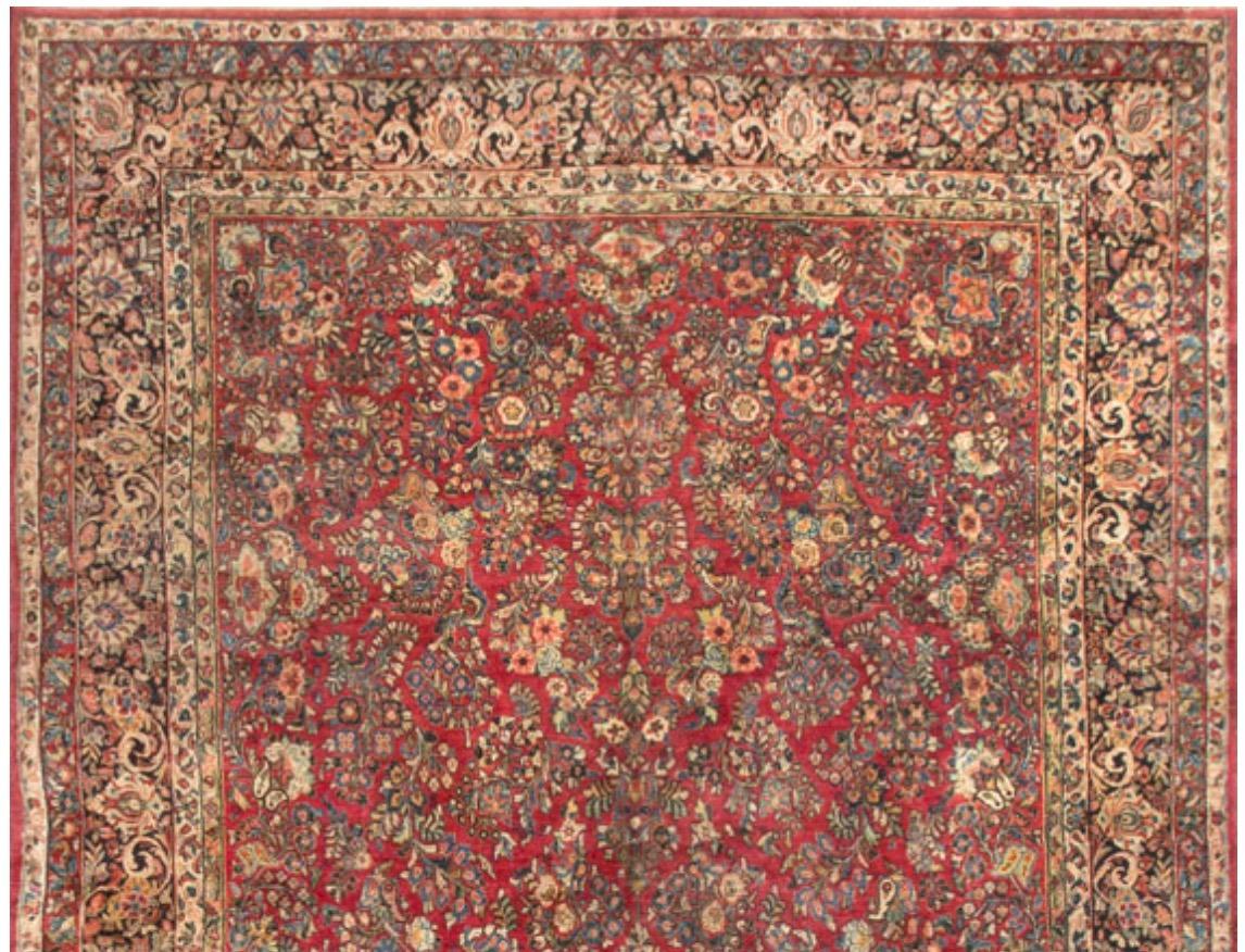Dieser Vintage-Sarouk aus den 1930er Jahren hat einen roten Grund, der mit floralen Mustern gefüllt ist und von einer marineblauen Bordüre umschlossen wird, die die floralen Elemente wiederholt. Sarouk-Teppiche stammen aus dem Dorf Saruk, das etwa