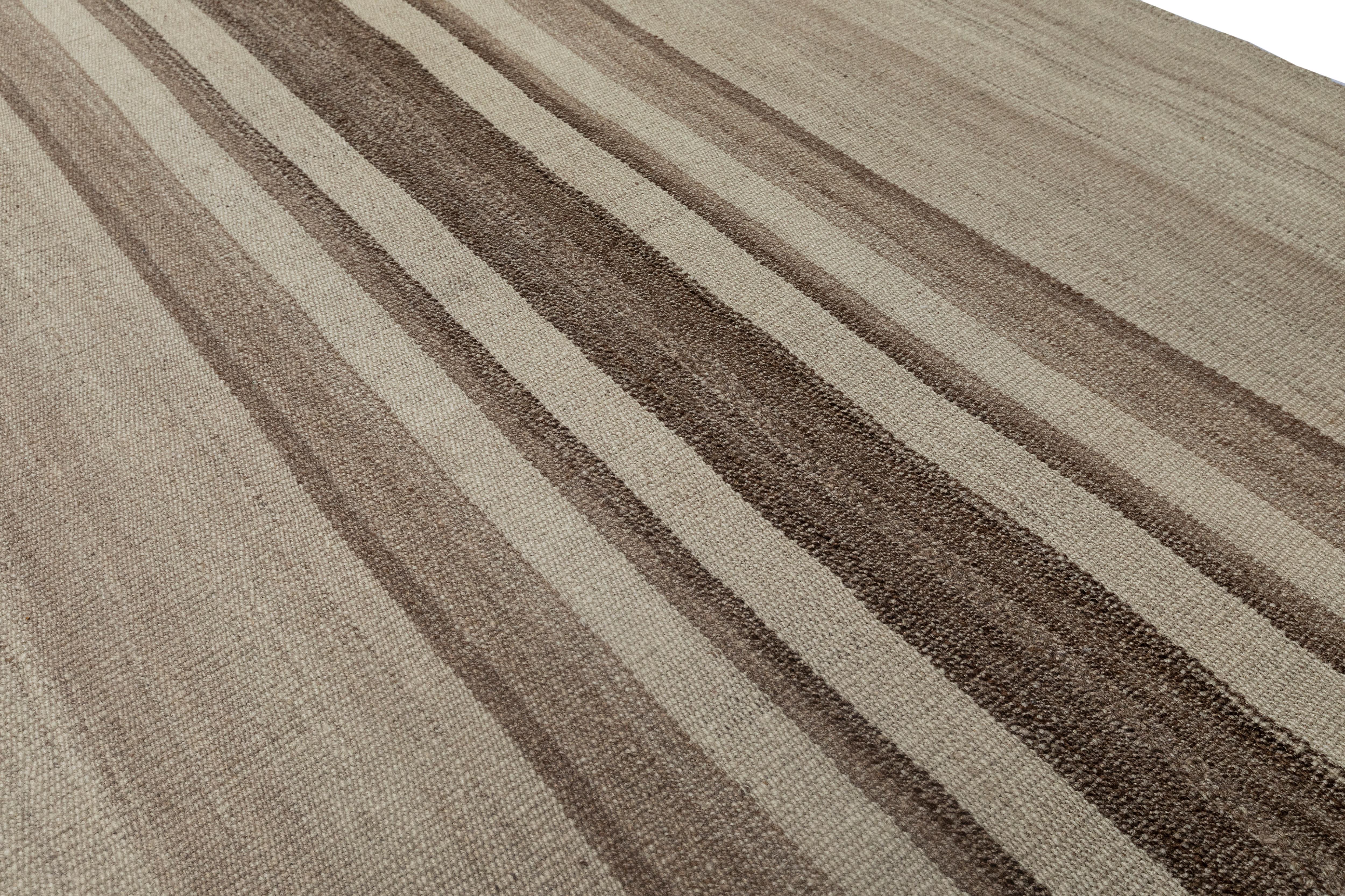 Questo elegante tappeto kilim vintage a tessitura piatta presenta un design a righe senza tempo in una serena tavolozza di toni naturali della lana, che vanno dal caldo taupe e dal morbido beige al delicato moka. Intrecciato a mano a metà del XX