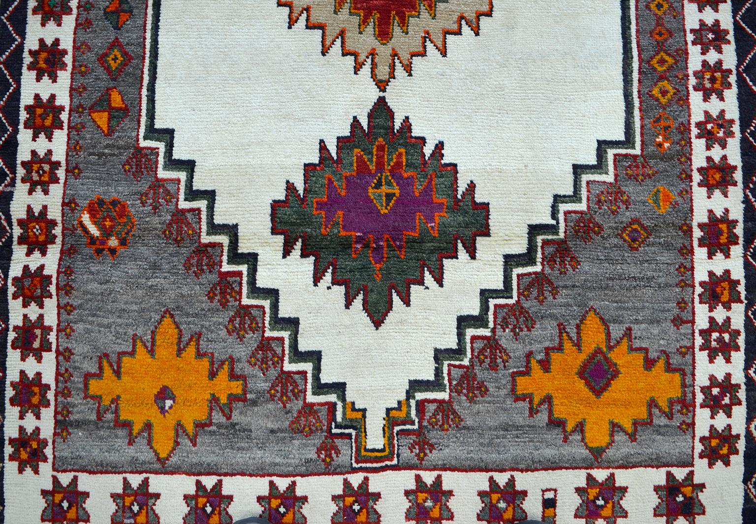 This vintage Persian Gabbeh carpet, circa 1940 in pure handspun wool and organic dyes exhibits unique coloration consisting of vegetable dyed and undyed wools. Deep green, vibrant orange and purple saturate its geometric motifs, while salt and