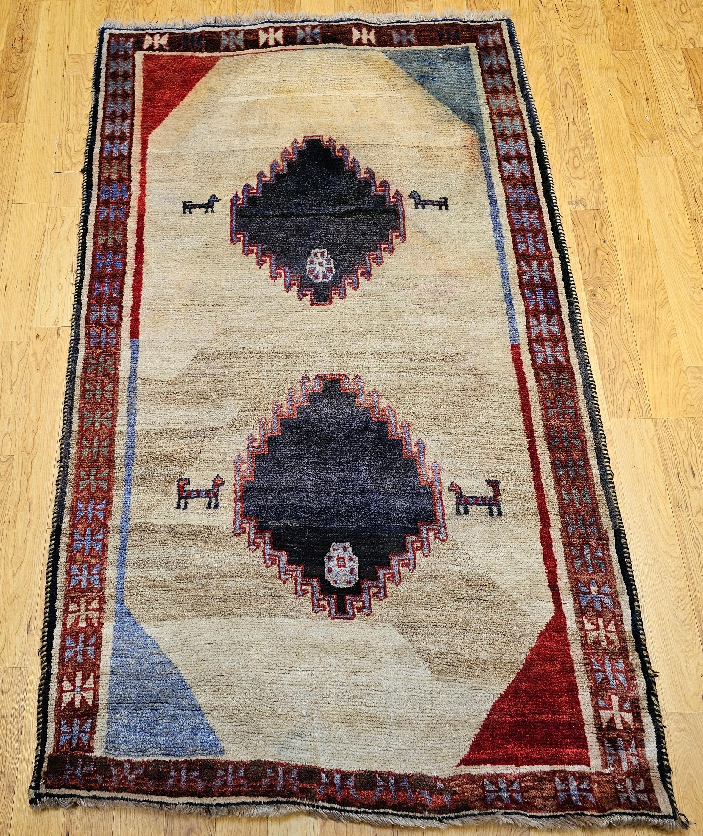 Bellissimo tappeto Gabbeh vintage proveniente dalla Persia.  Il tappeto ha un bel design moderno e colori chiari con un campo di paglia o beige e accenti di blu e rosso.  Il tappeto è stato annodato interamente a mano con un vello di lana su una