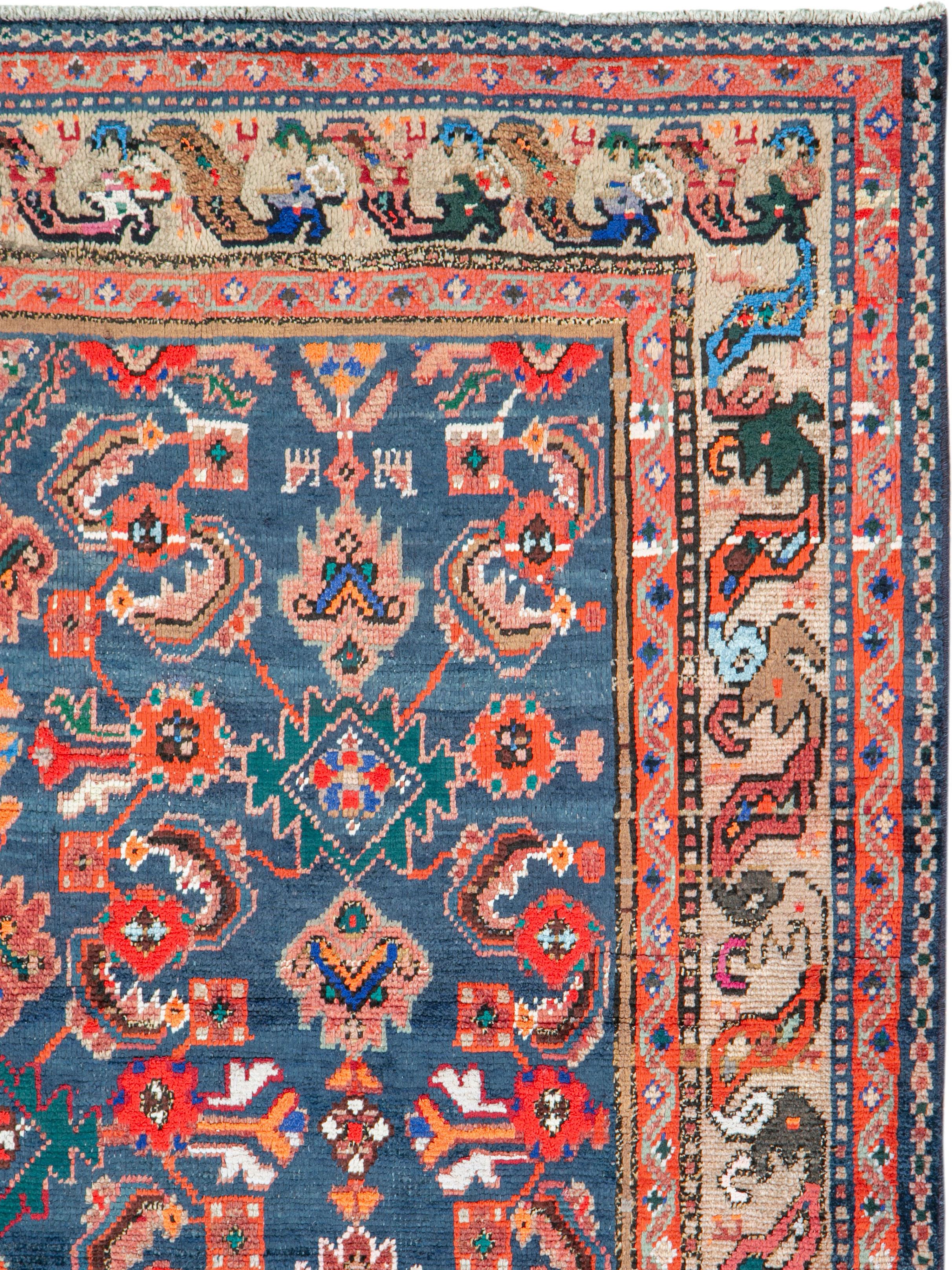 A vintage Persian Hamadan rug. The blue field abrashes (natural color striations) from dark to medium while displaying a classic Herati design accented with white cotton and showing small interstitial animals. The sand-putty border features the