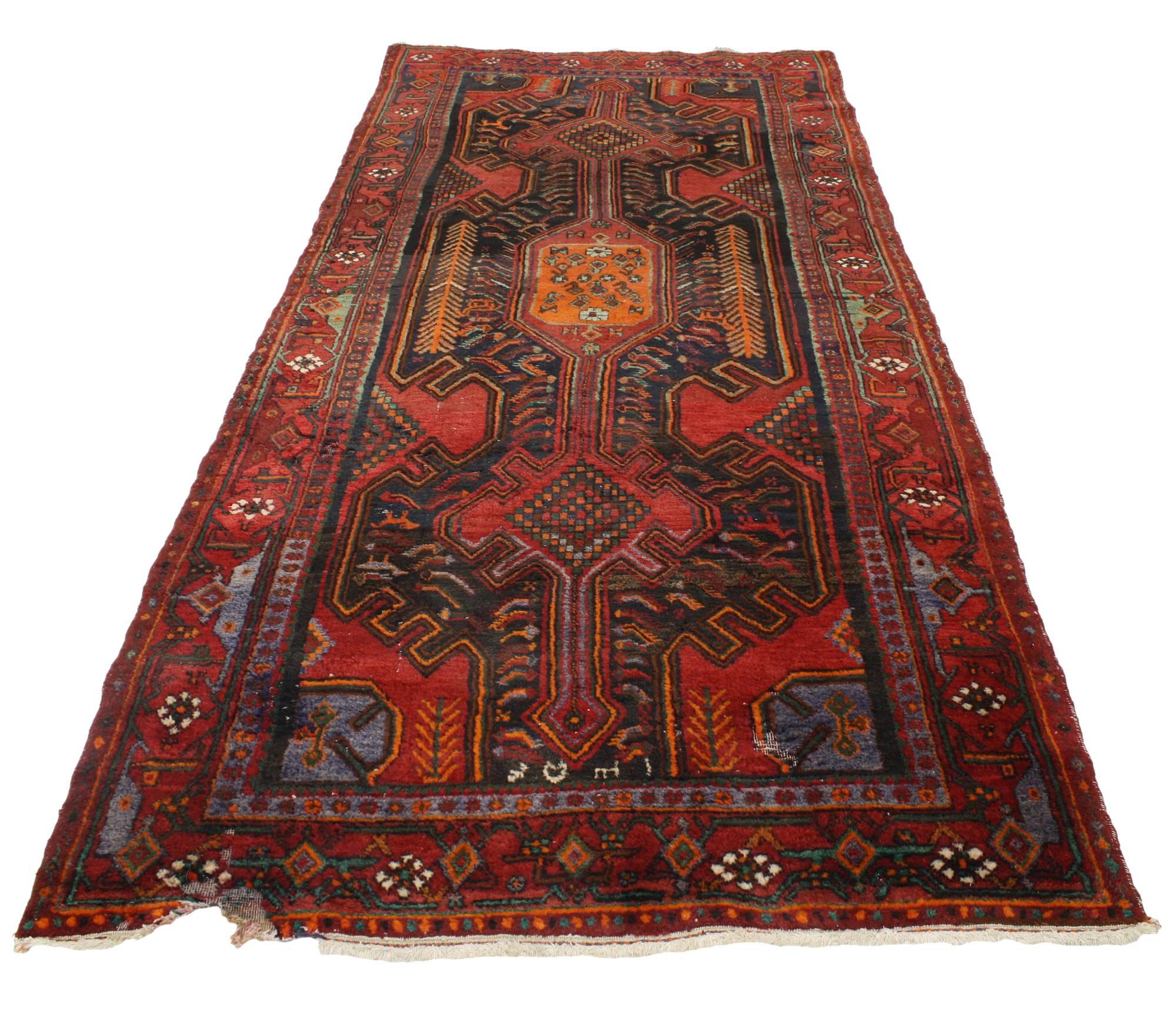 76898, a vintage Hamadan rug with geometric hunting design. This hand-knotted wool vintage Persian Hamadan rug features the perfect amount of wear and displays a centre row of geometric symbols dotted with tiny flowers on a field of deep red.