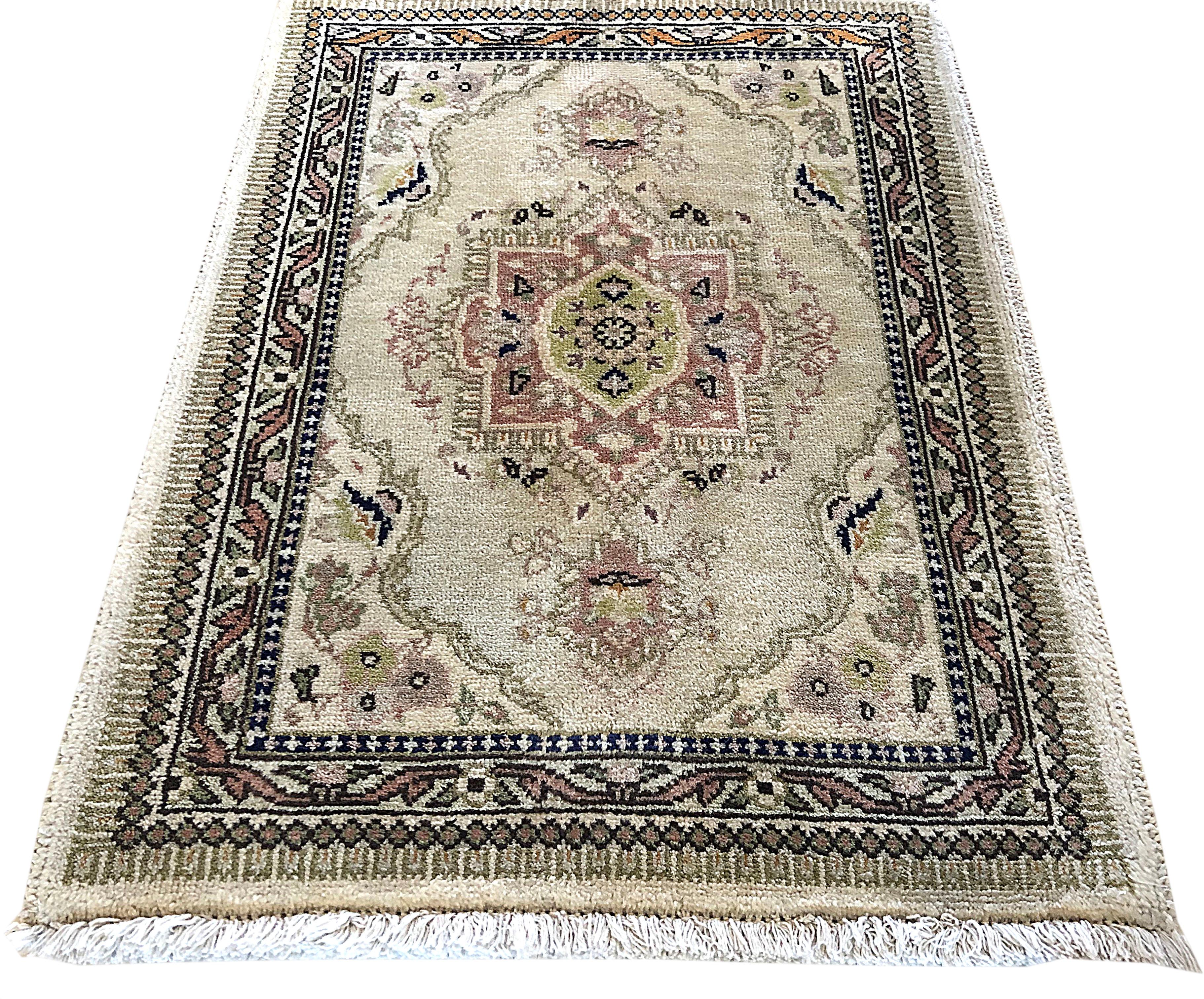 This little rug is knotted in Iran. The design is open field medallion floral. The pile is wool with cotton foundation. The base and border colors are cream. The size is 2 feet wide x 2 feet 6 inches tall.