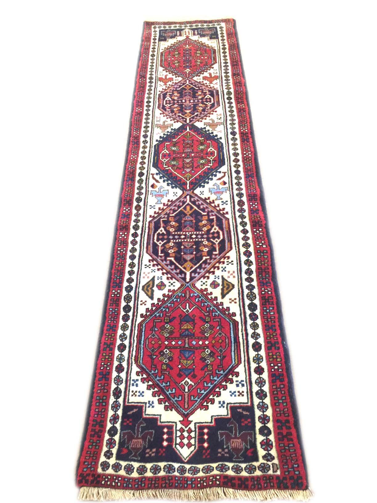 This runner is knotted in the province of Azarbayjan in north-west of Iran. The design is geometric with repeated medallion. The pile is wool with cotton foundation. The base color is cream and the border is red. The design and color combination can
