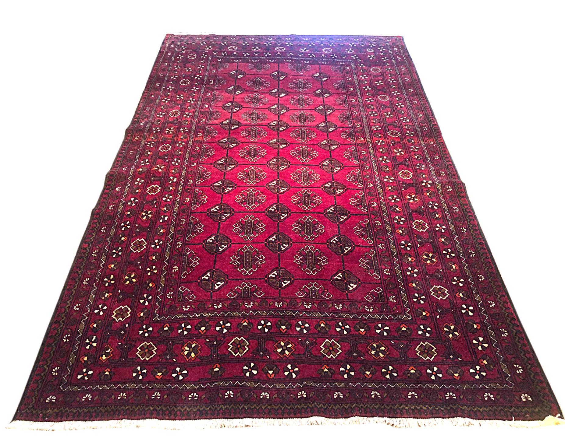 Cet authentique tapis persan Baluchi a des poils et une base en laine qui sont noués à la main par les nomades de Baluchi. L'âge de ce tapis est de presque 50 ans. La couleur de base et les couleurs des bordures sont rouges. La taille de ce tapis