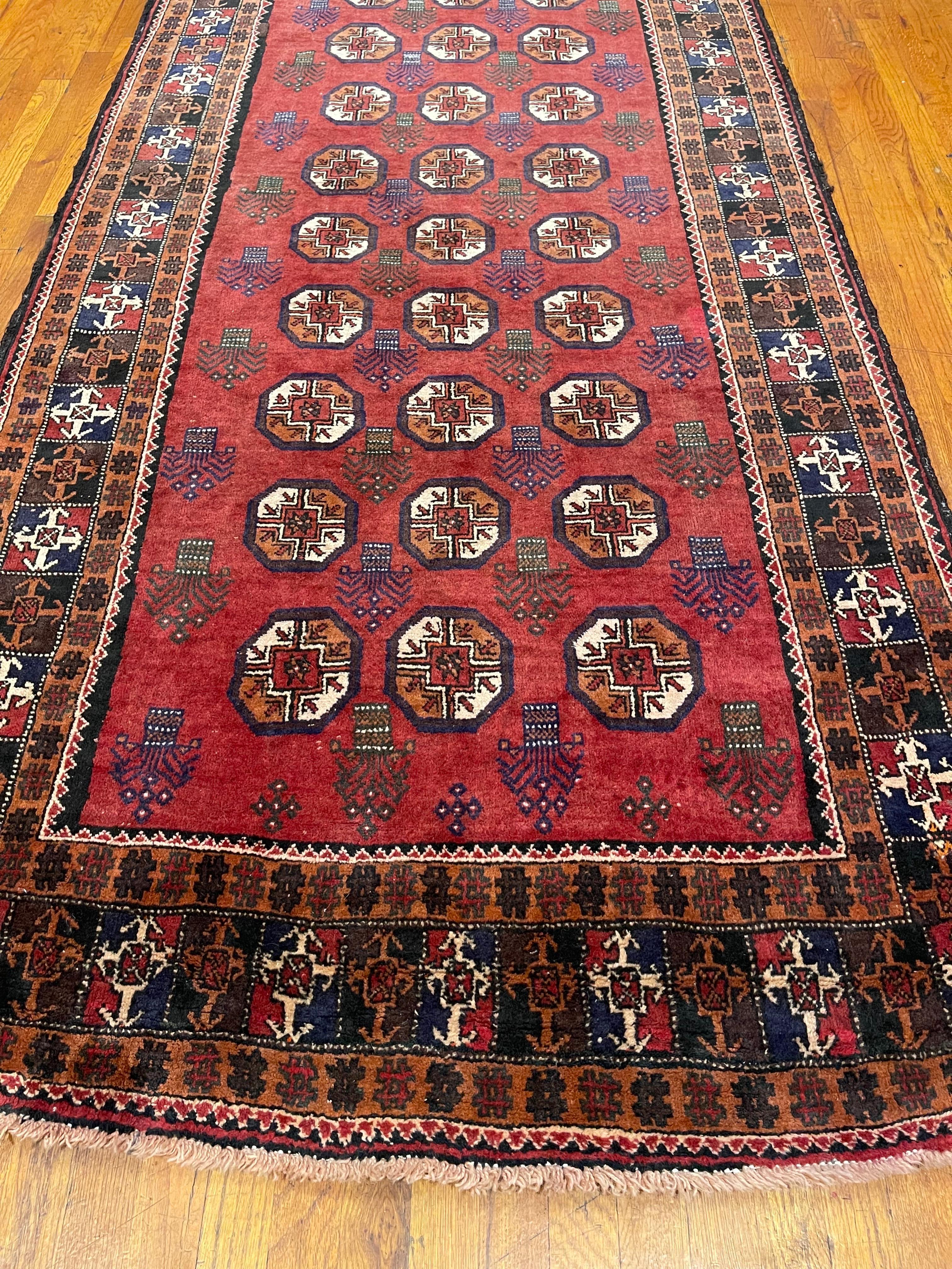 This authentic Persian Baluchi rug has wool pile and foundation which are hand-knotted by the nomads of Baluchi. The age of this rug is almost 50 years old. The base color is rust with multi shades of brown and rust in the border. The size of this