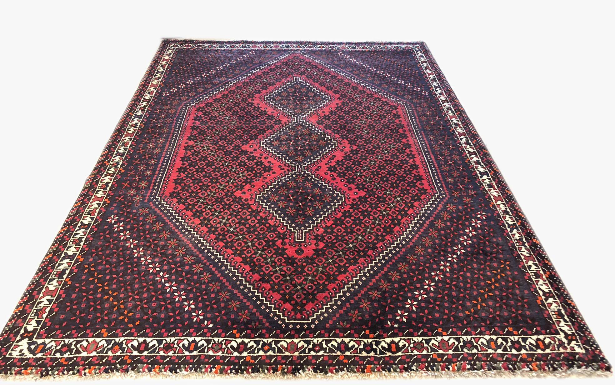 Dieser Teppich ist ein authentischer Teppich aus dem Iran, Shiraz. Der Flor und die Unterlage bestehen aus Wolle. Die Grundfarbe ist rot und dunkelbraun. Das Design ist geometrisch mit einem sich wiederholenden Rautenmedaillon. Dieses Stück eignet