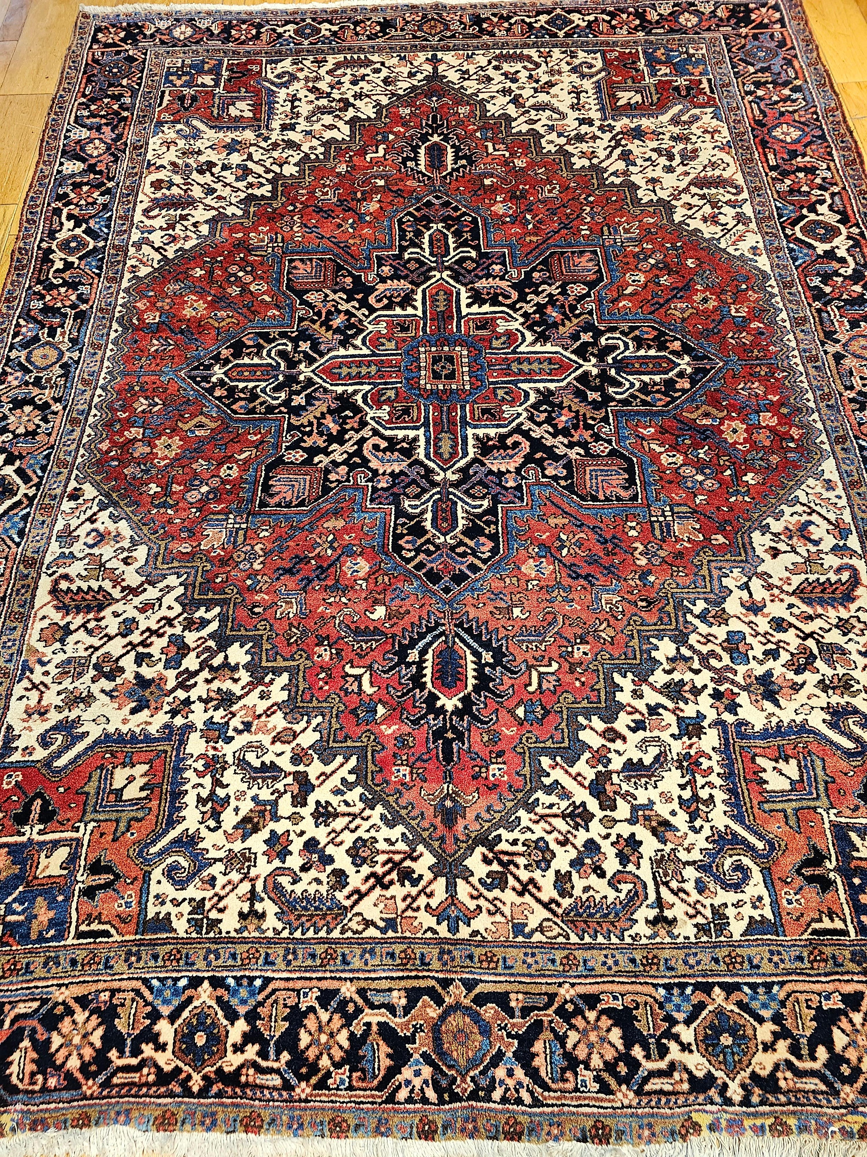 Vintage Persian Heriz room size rug from the 2nd quarter of the 20th century. The large central medallion in this Heriz rug is in a  blue color and is set in a brick red background color framed with ivory, red, and French blue colors spandrels. The