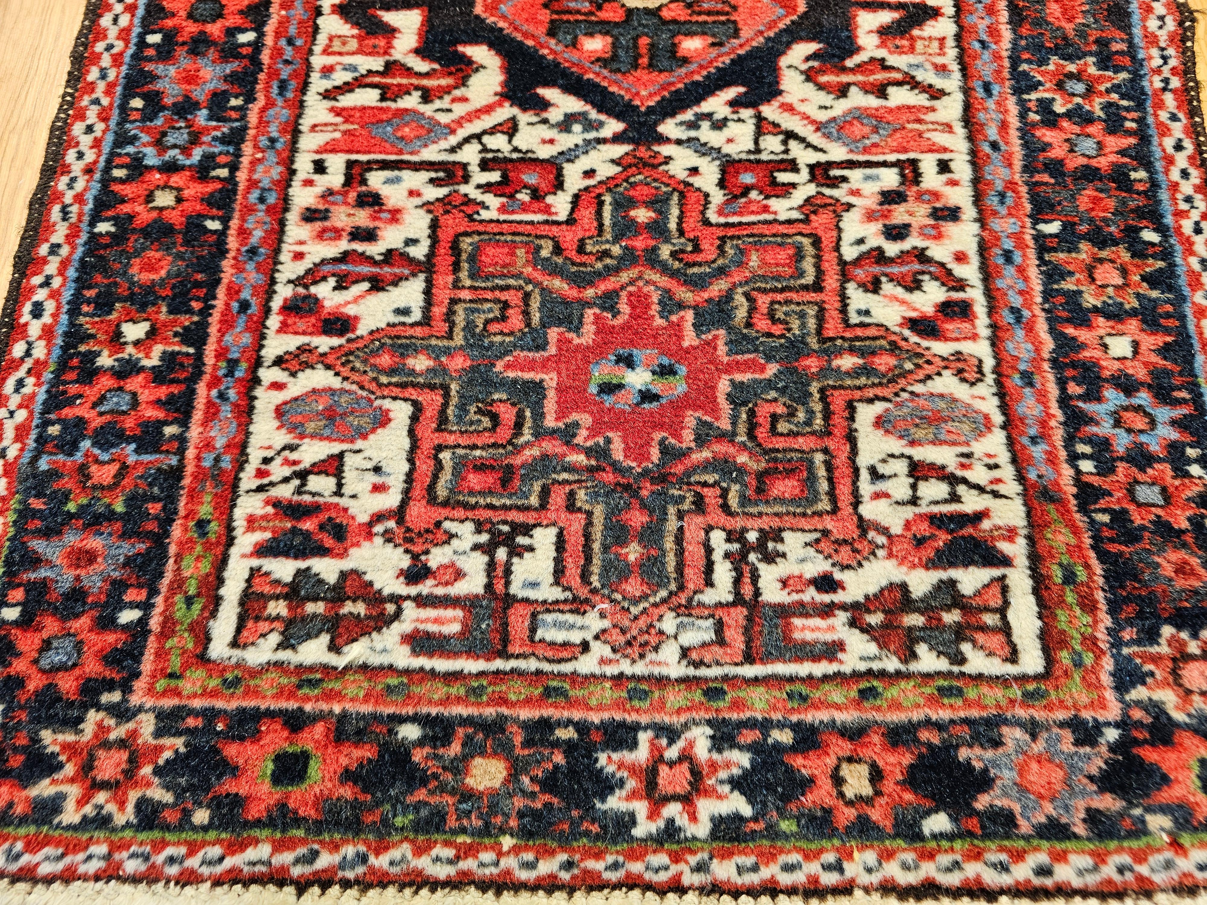 A vintage Persian Heriz Karajeh rug from the early 20th century featuring three medallions in green and red set on a cream field with a navy border. Hand-knotted with exceptional craftsmanship, this piece offers bold geometric artistry and timeless