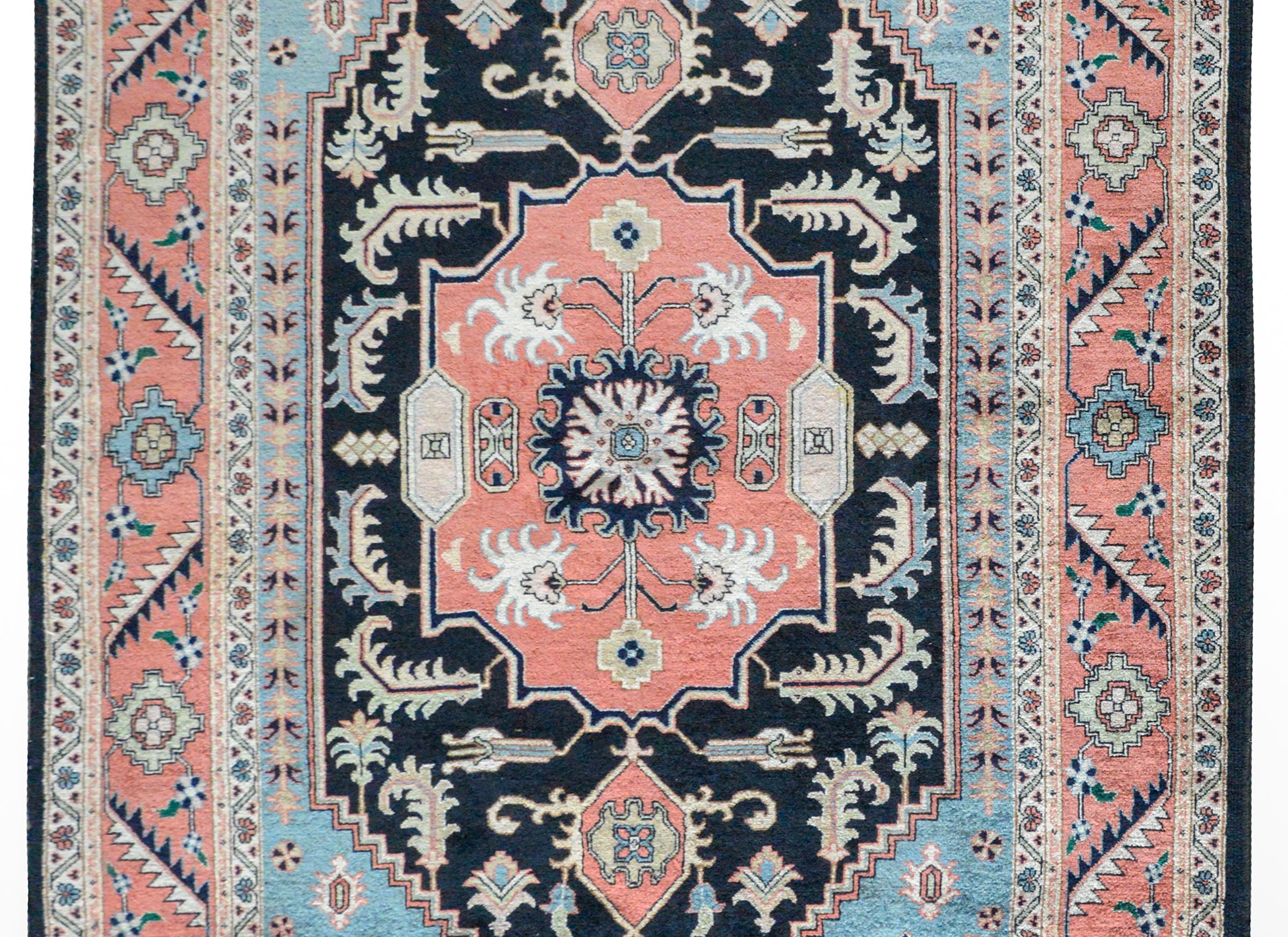 A beautiful vintage Persian Heriz rug woven with a central floral medallion amidst a field of more bold stylized flowers, and surrounded by a wide floral and leaf pattered border, all woven in muted reds, blues, and yellows.