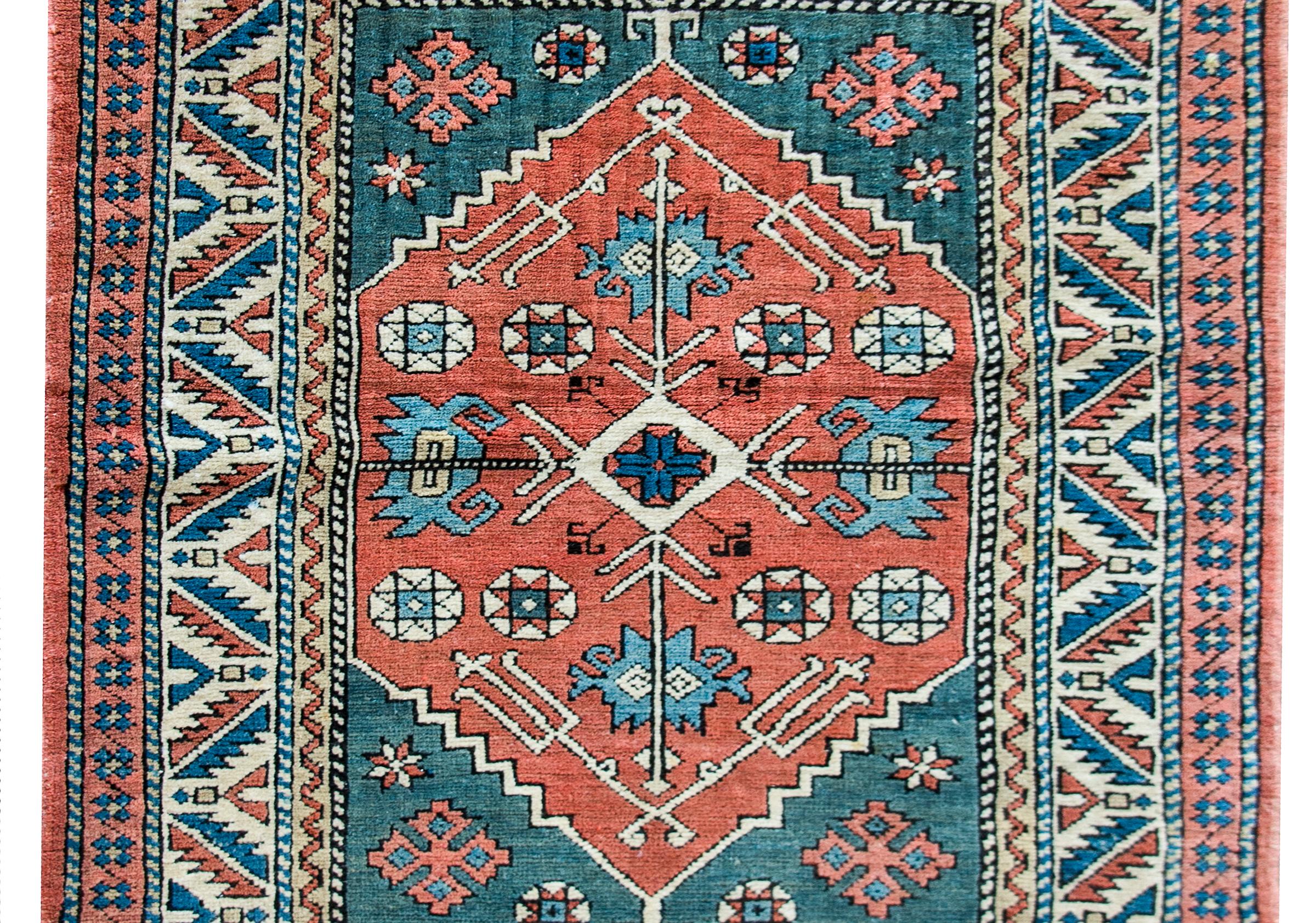 A beautiful late 20th century Persian Heriz rug with a sweet medallion with four flowers woven in indigo, green, and yellow, against a coral colored background. The border is wonderful composed with multiple geometric and stylized floral patterns