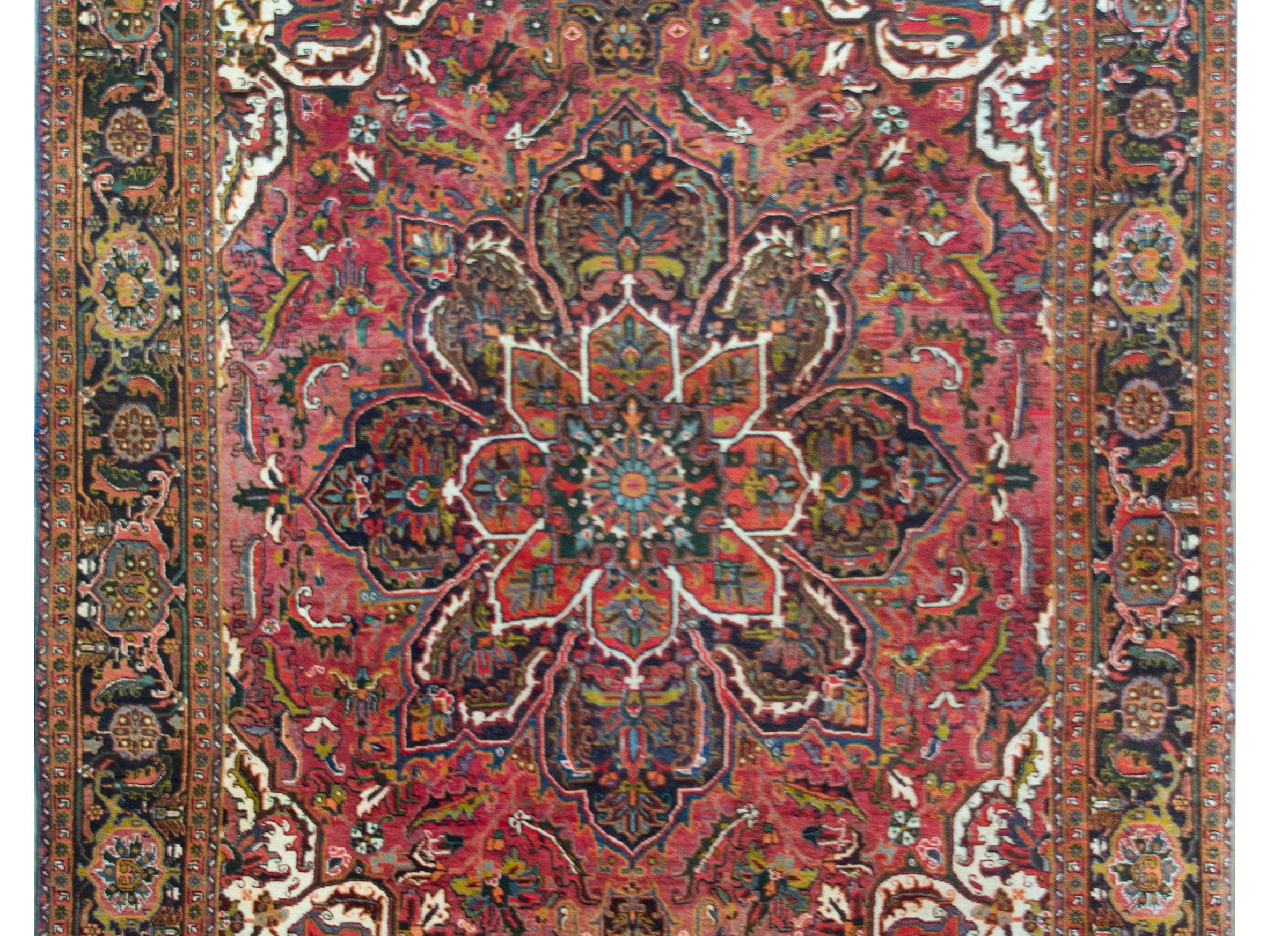 A mesmerizing vintage Persian Heriz rug with a large central floral medallion with an intensely woven floral, leaf, and scrolling pattern woven in myriad colors including crimson, green, orange, violet, and light and dark indigo, and surrounded by a