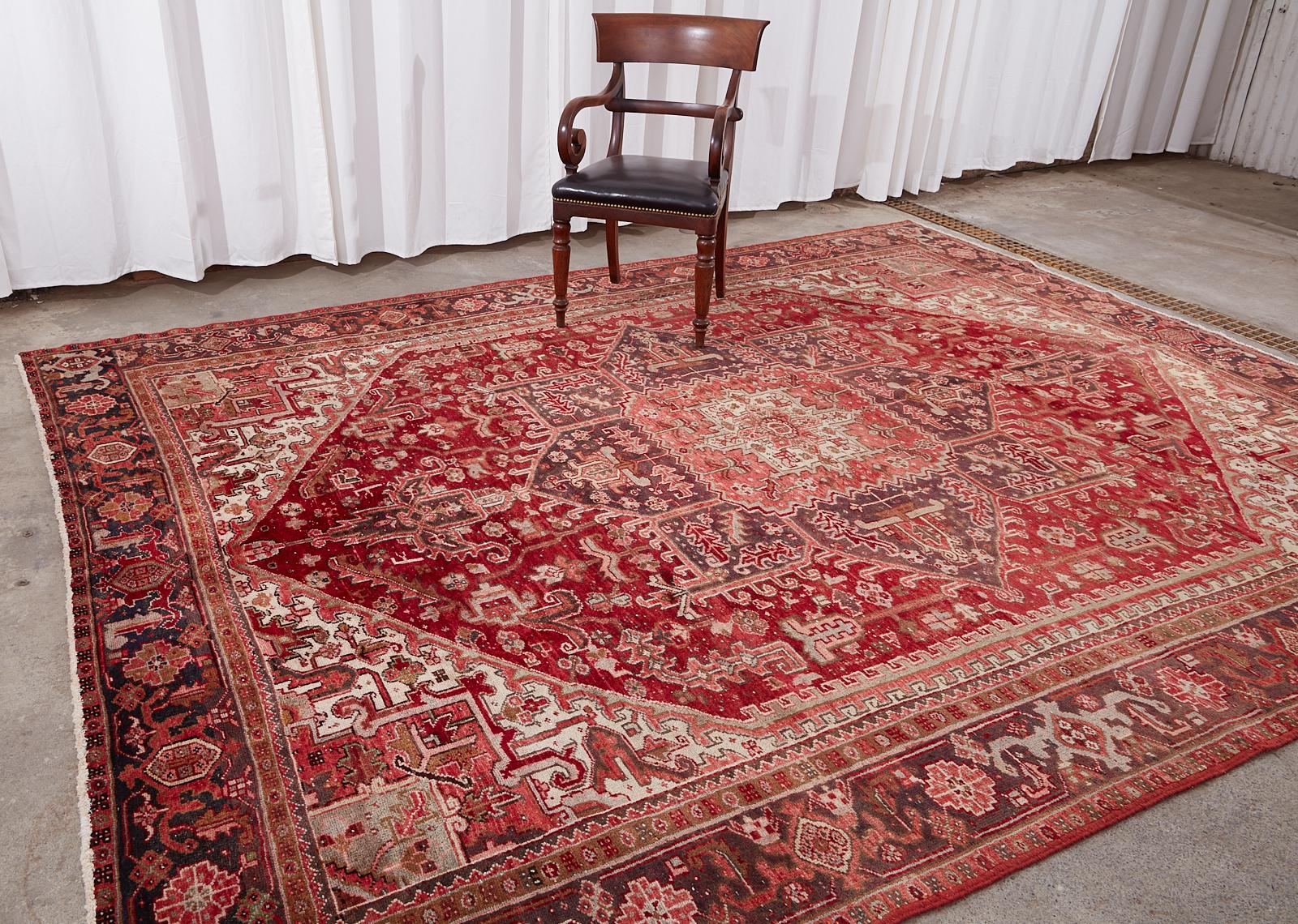 Traditionally styled vintage Persian Heriz rug crafted from hand-knotted wool. The rug features a large multi-faceted geometric star medallion with pendants. The field has triangular corners with interesting white ground accents. Stylized floral