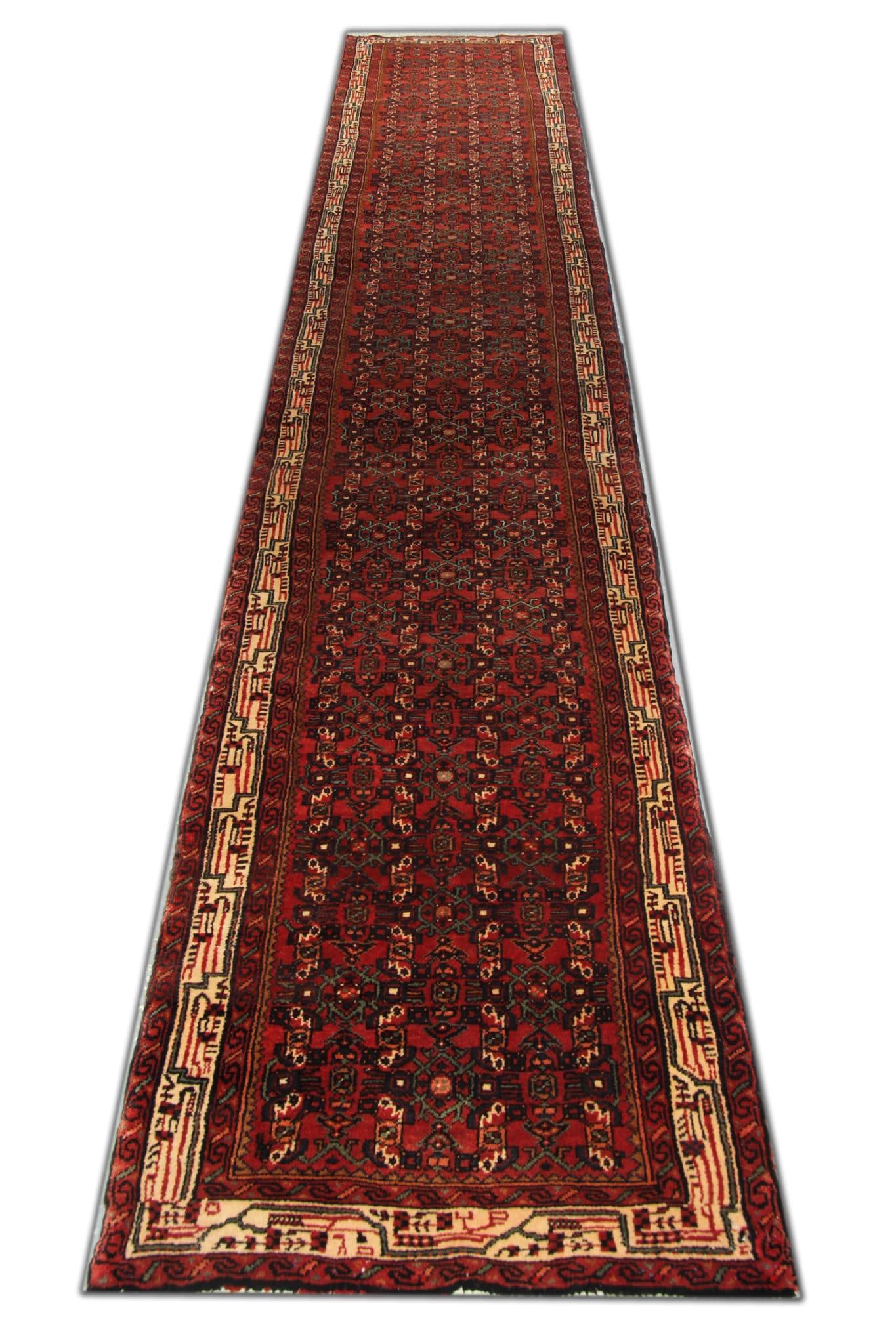 Crafted in the 1950s, this vintage runner rug exudes timeless charm and character, with its deep red and burgundy hues adding warmth and sophistication to any space. The hand-knotted wool pile, complemented by a sturdy cotton foundation, ensures