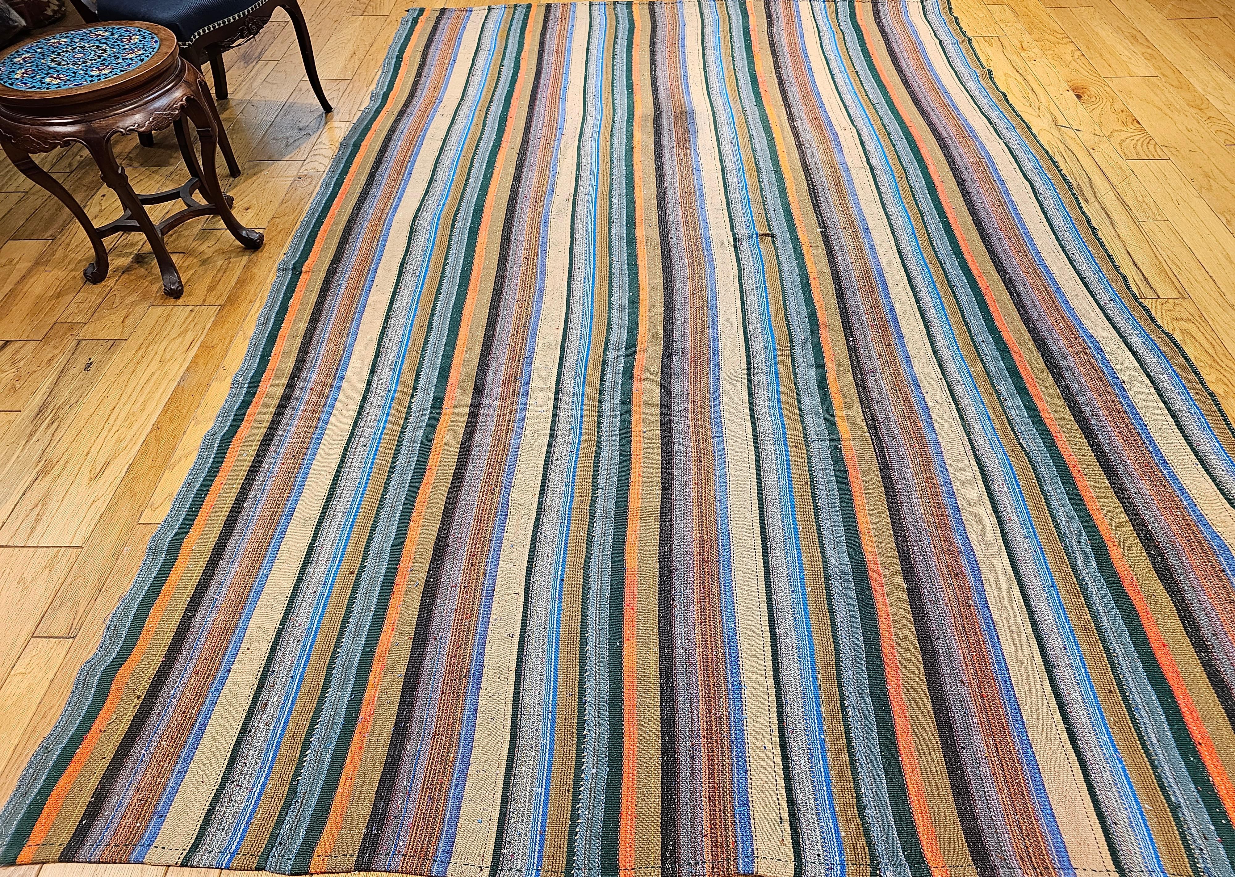Vintage Persian Jajim Kilim flachgewebter Teppich mit bunten Streifen. Dieser handgewebte Jajim-Kilim hat Streifen in verschiedenen Farben, darunter blau, grün, rot, orange, braun, grau, gelb und lila.  Der Jajim-Kelim wurde durch Zusammennähen von