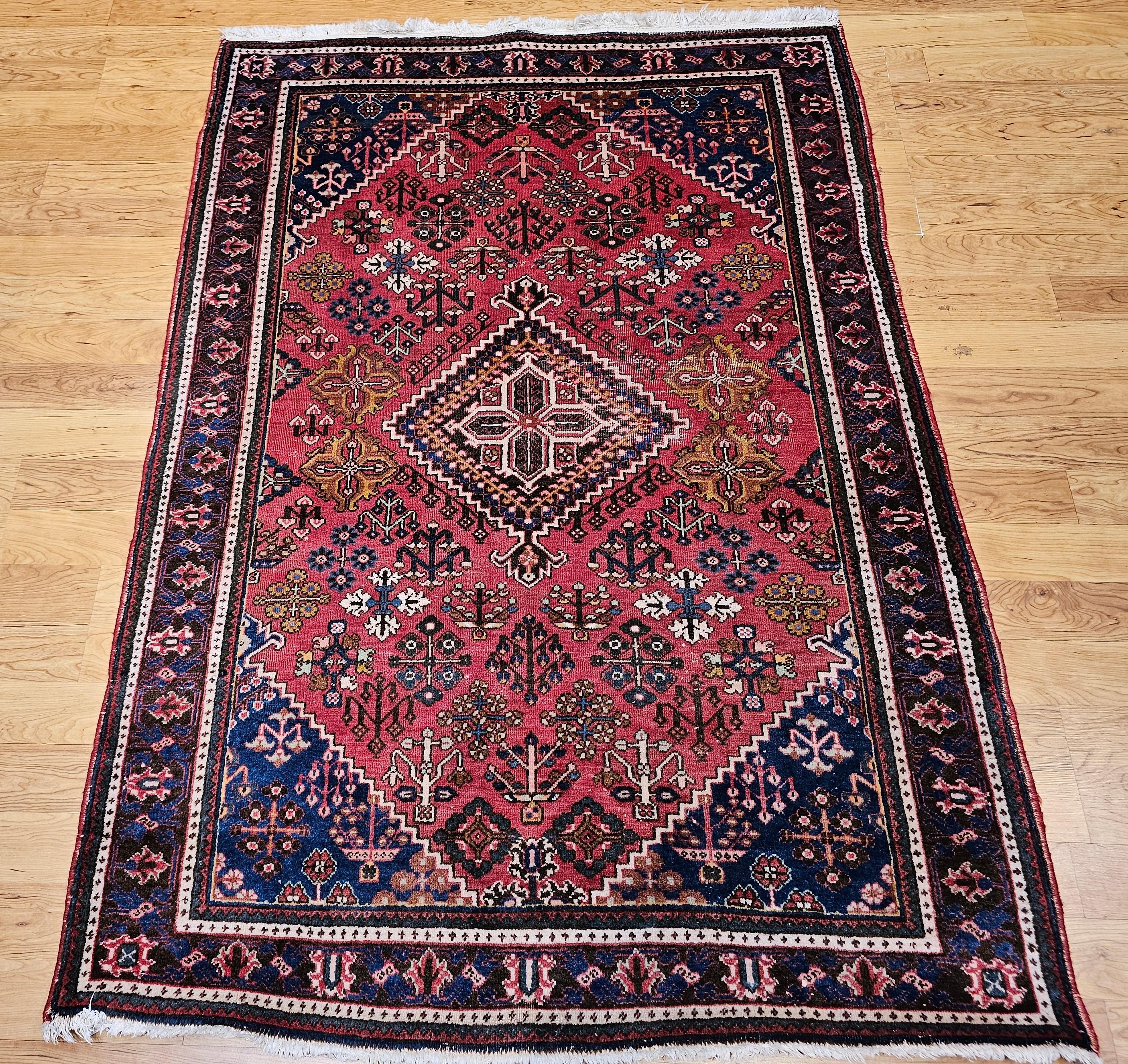 Vintage hand knotted Persian Joshegan area rug in a geometric pattern in a rust red background with corner spandrels in French blue is from the mid 1900s.  This amazing antique Joshegan rug from 1920s Iran was handwoven and bears a remarkably unique