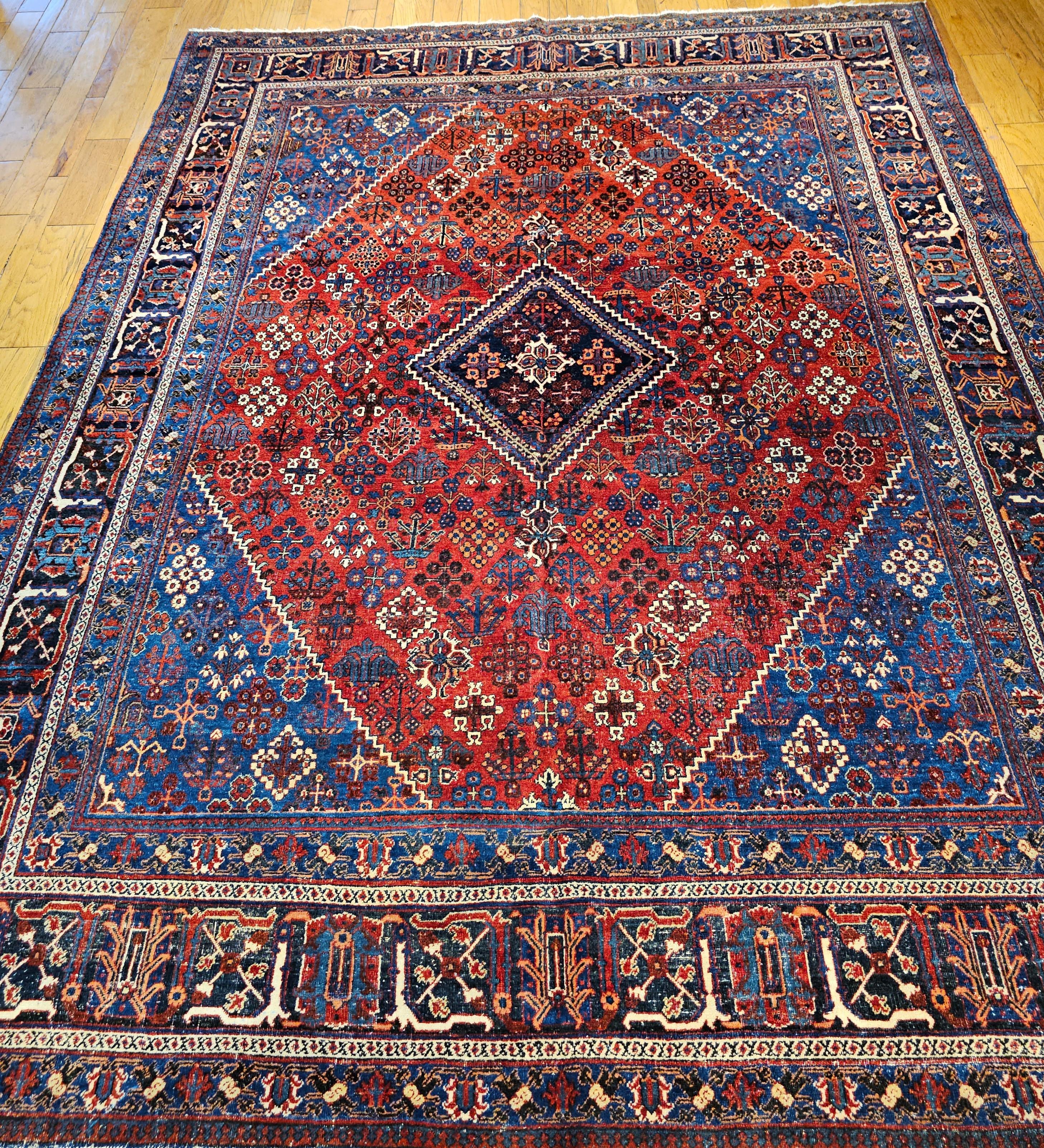 Vintage Persian Joshegan room size rug in a geometric pattern in a rust red background with corner spandrels in French bleu is from the early 1900s.  This amazing antique Joshegan rug from 1920s Iran was handwoven and bears a remarkably unique