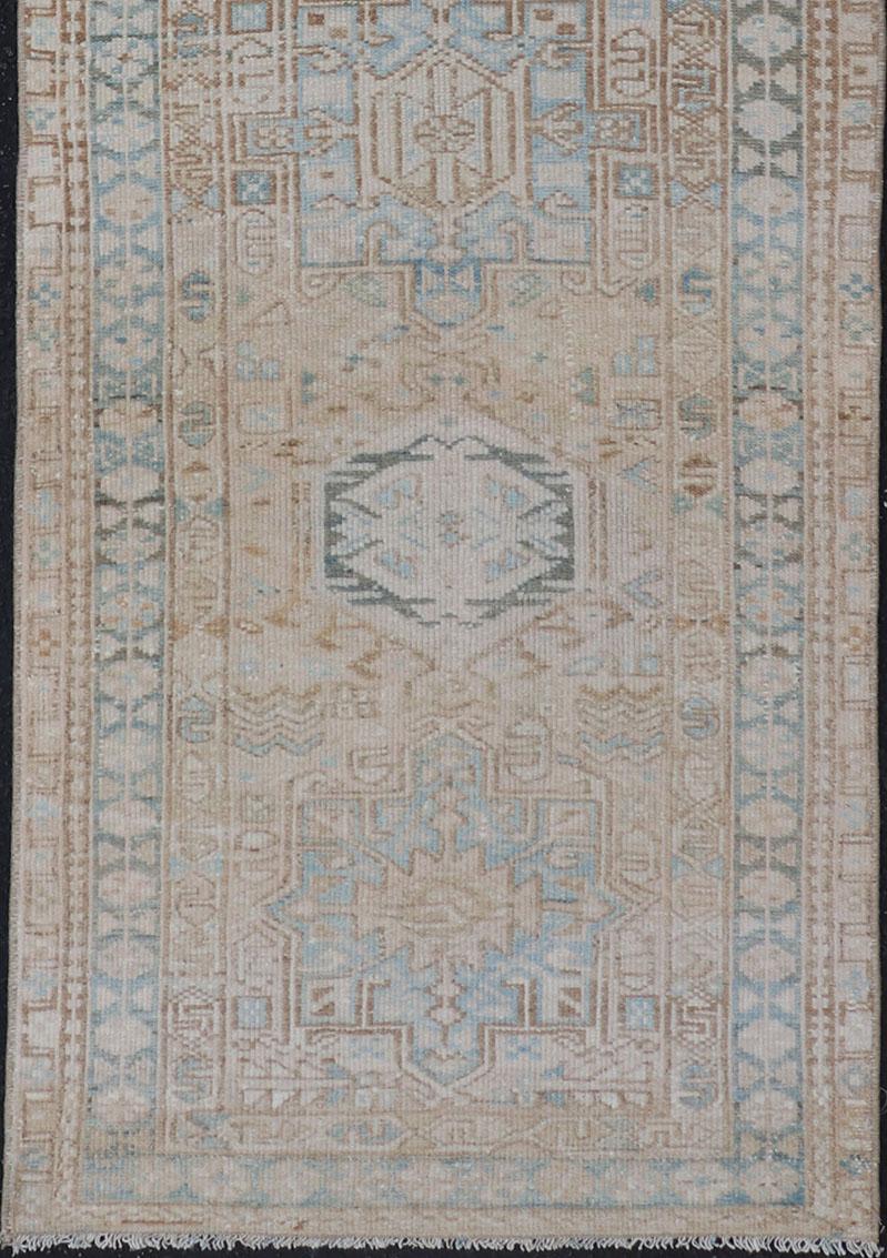 Alfombra persa vintage Karadjeh con medallones en tonos tierra y contornos azul claro y marrón. Un borde complementario de varios niveles abarca la totalidad de la pieza; lo que la convierte en una maravilla para una gran variedad de