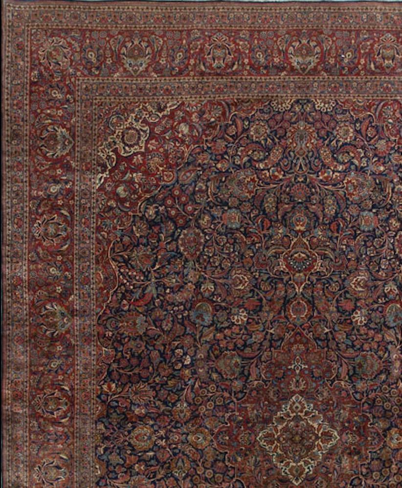 The central navy field filled to capacity with floral motifs that all surround a lighter central medallion. Enclosing the field the main border repeats the floral theme in this oversize 1920s Kashan from central Persia. Size: 13'7