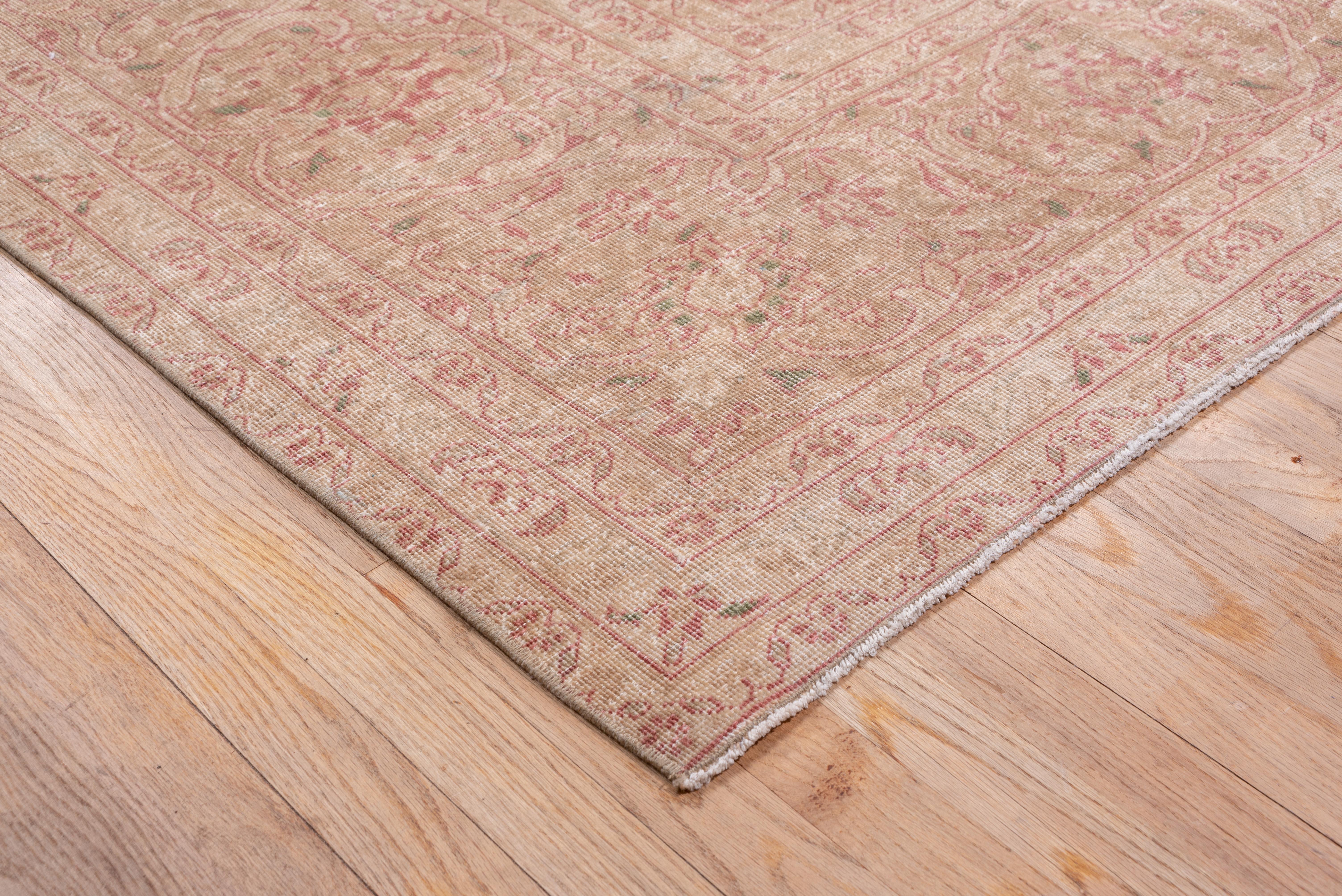 This all-over worn to near distress central Persian city carpet shows a red field in a Shah 'Abbas palmette and vinery pattern supporting a barbed warm light brown medallion, with semi-en suite off white and brown corners. Light brown border with