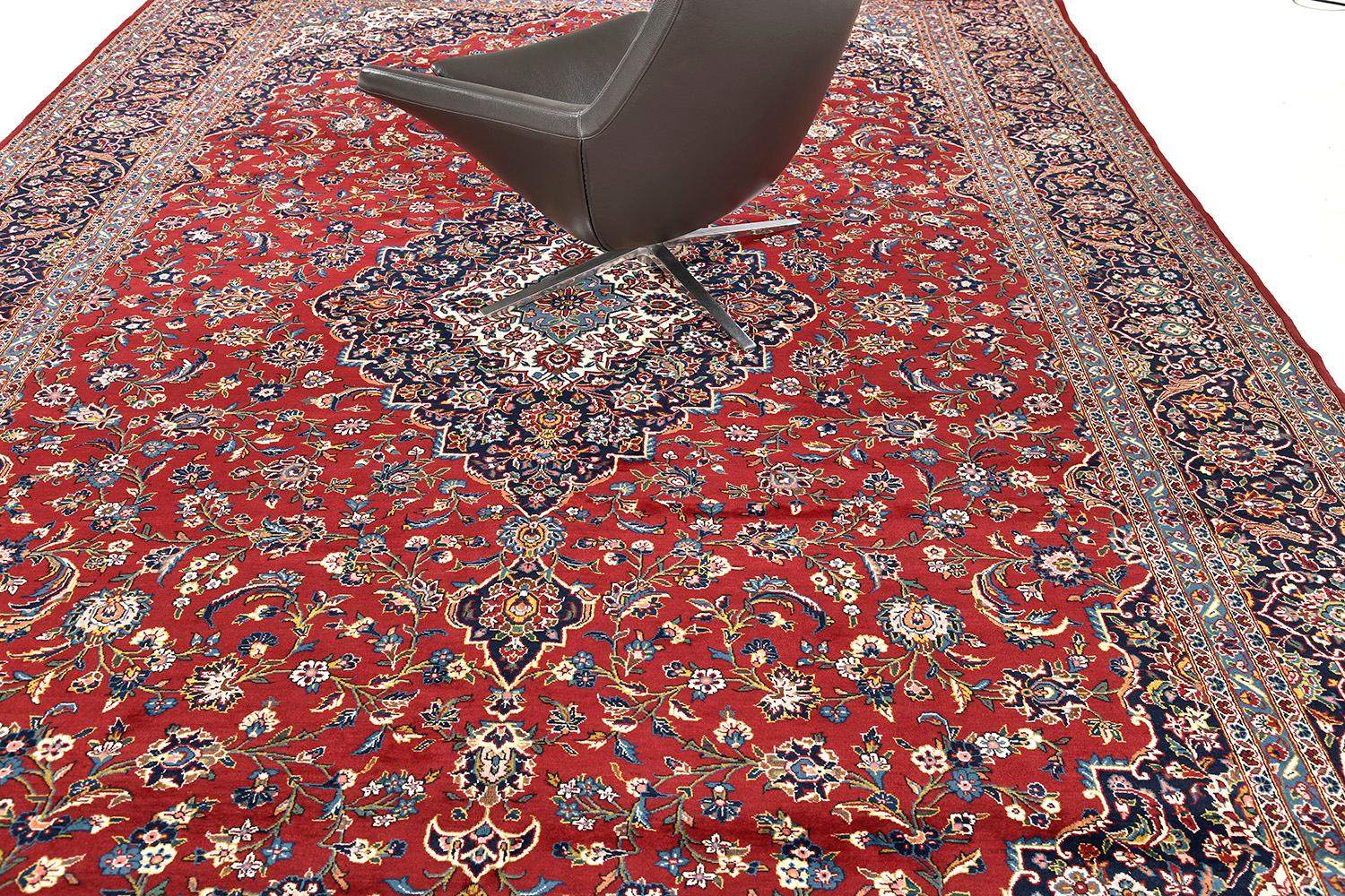 An outstanding masterpiece of Kashan rug that features a penny-worth impact from its every design. At its core, majestically presents a detailed floral theme and leafy scrolls. An effortless combination of various symmetrical symbolic motifs is in