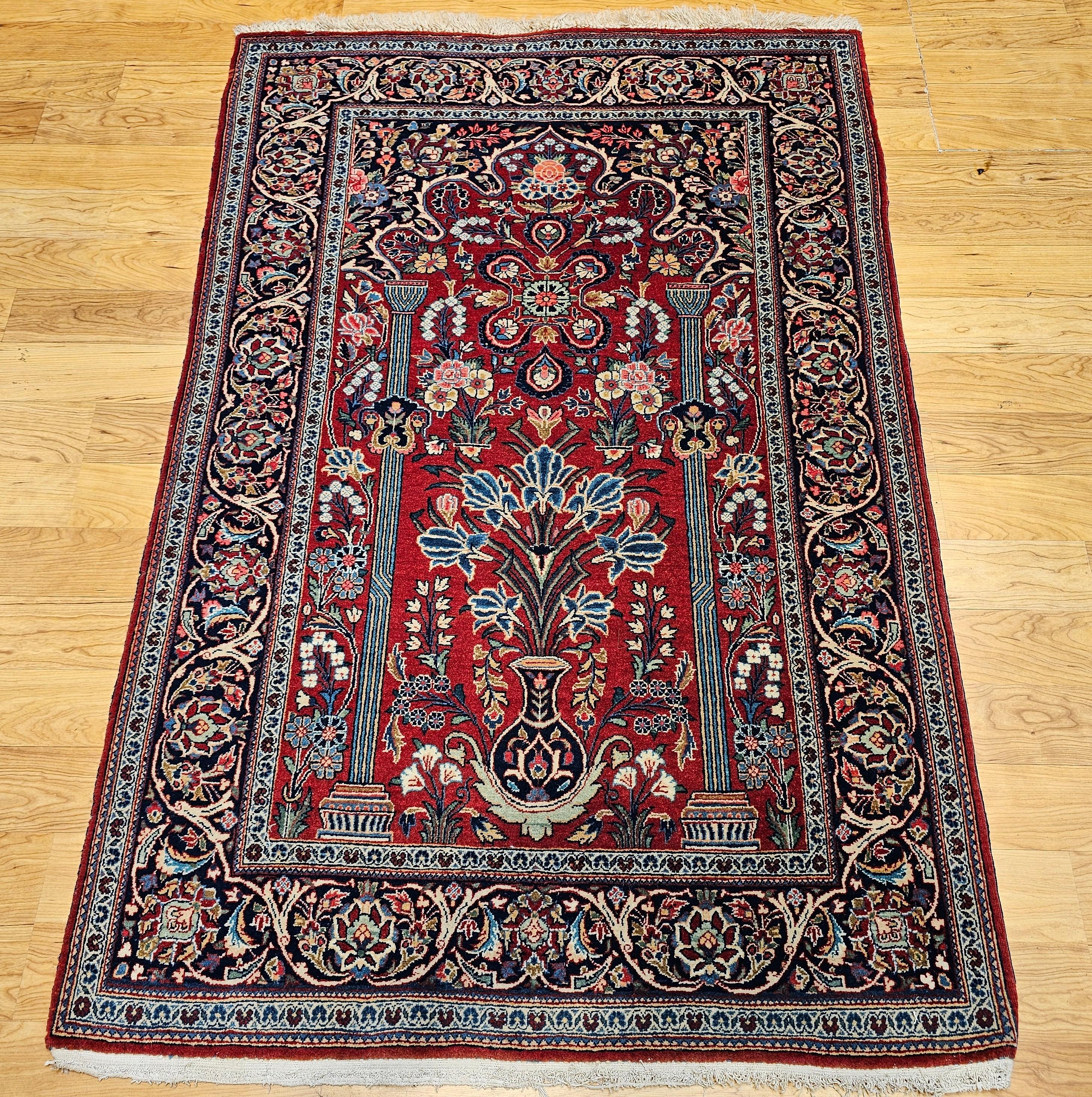 Vintage Persian Kashan pictorial area rug in a vase pattern in red, blue, ivory, green, and navy .  The pictorial area rug has a very rich and unique red color  background with designs in royal blue, green, ivory and navy. The rug has a navy blue