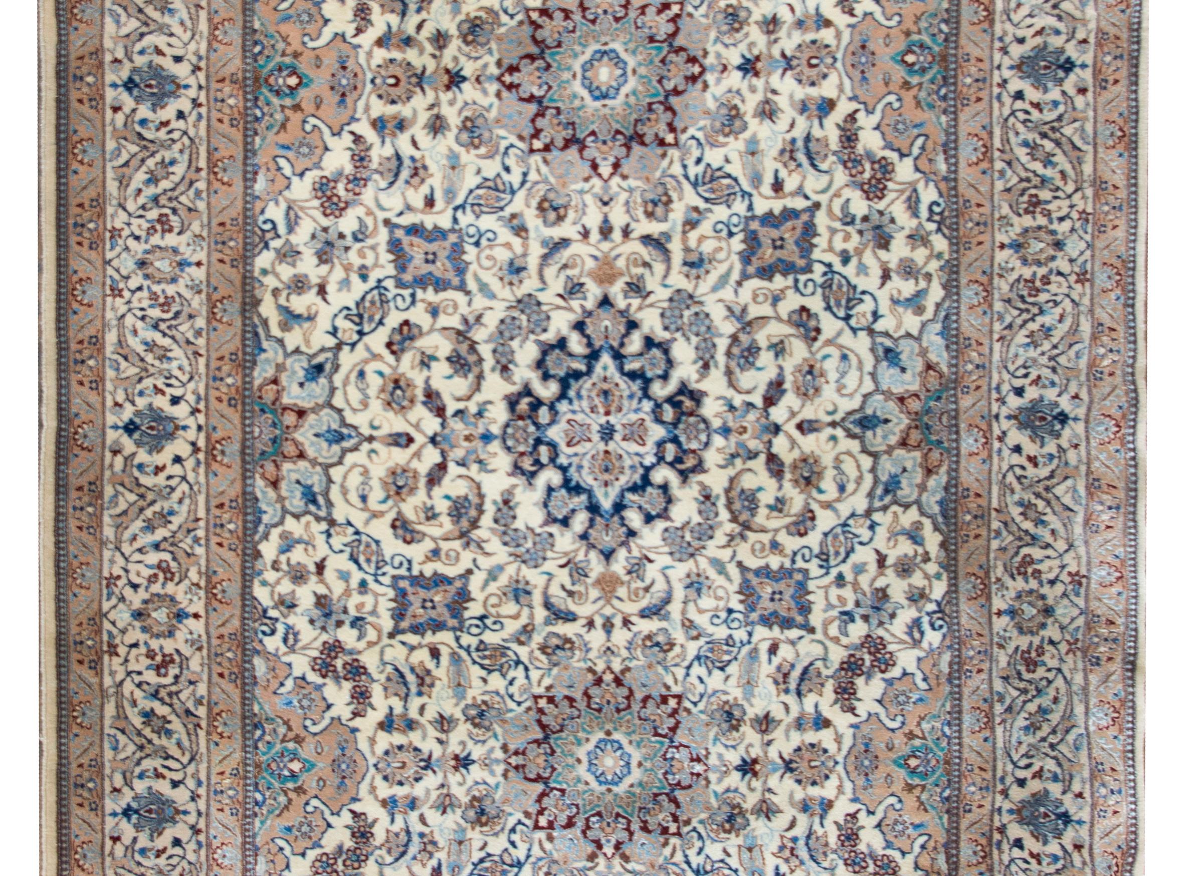A wonderful late 20th century Persian Kashan rug with an elaborate all-over pattern woven with myriad large and small flowers, and scrolling vines, surrounded by a complex border with a wide central stripe with repeated large-scale flowers flanked