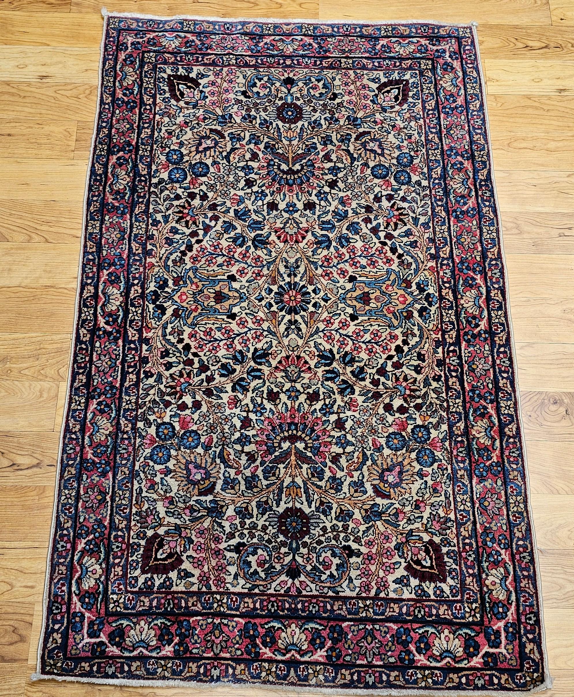 An astonishingly beautiful and colorful Persian Kerman Lavar area rug in floral design in ivory background with design colors in red, pink, green, blue and many others.  The rug has a gorgeous design and wonderful color combination.  The rug has one
