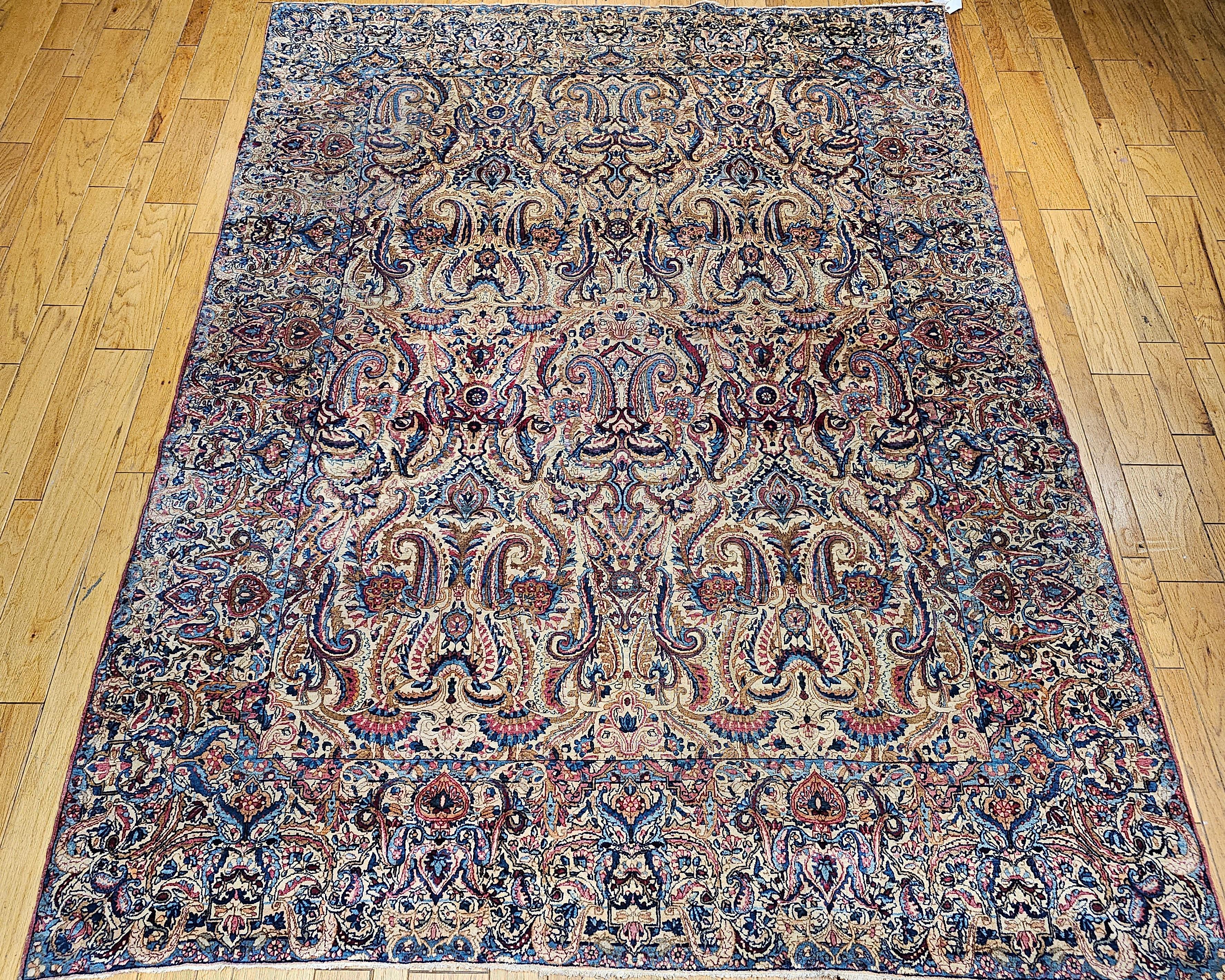This rare near-square vintage Persian Kerman Lavar rug, woven in the first quarter of the 1900s, showcases a remarkable all-over large paisley pattern — a striking expression of classical Persian artistry. Set against a refined ivory background, the