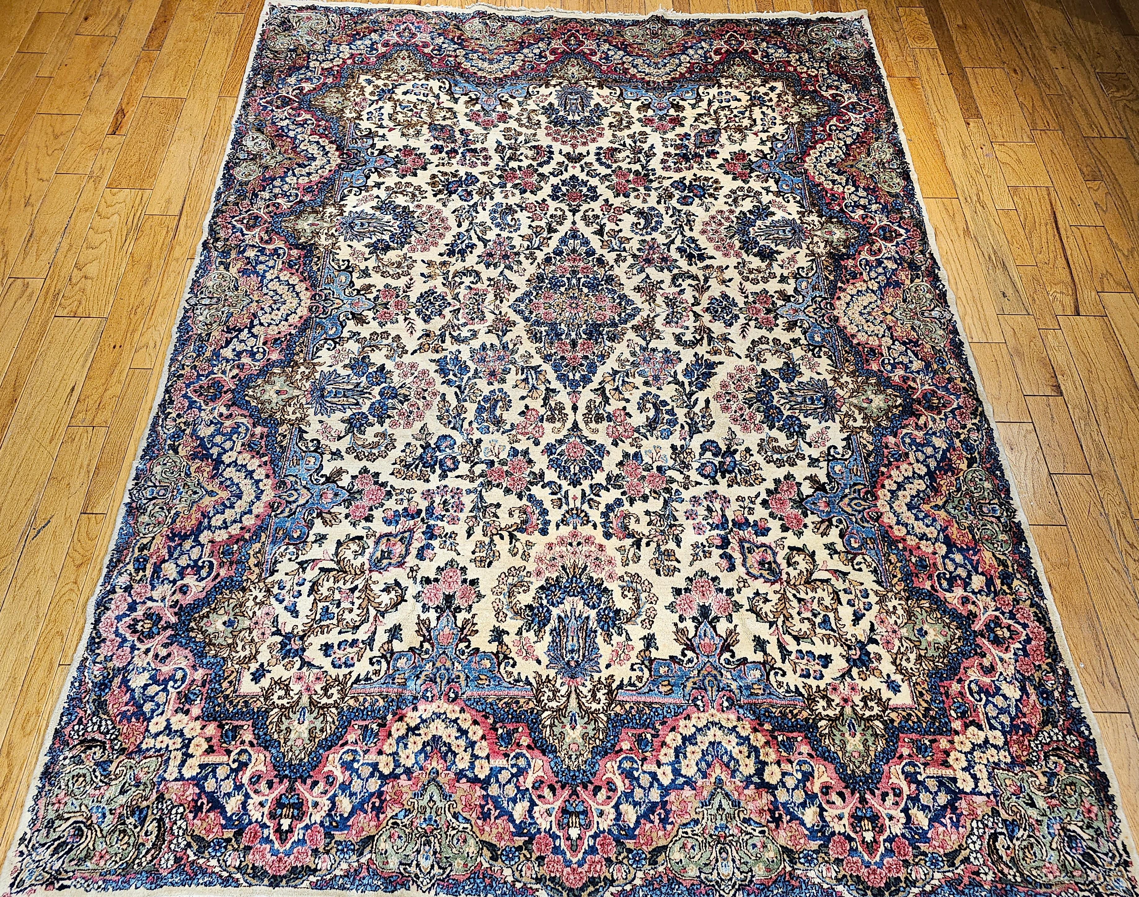 Vintage Persian Kerman Lavar room size  rug in an all-over floral pattern from the early 1900s.  The beautiful Kerman has a floral pattern with flower bouquets in various colors throughout the field in ivory,  red, pink, blue, yellow, and green. 