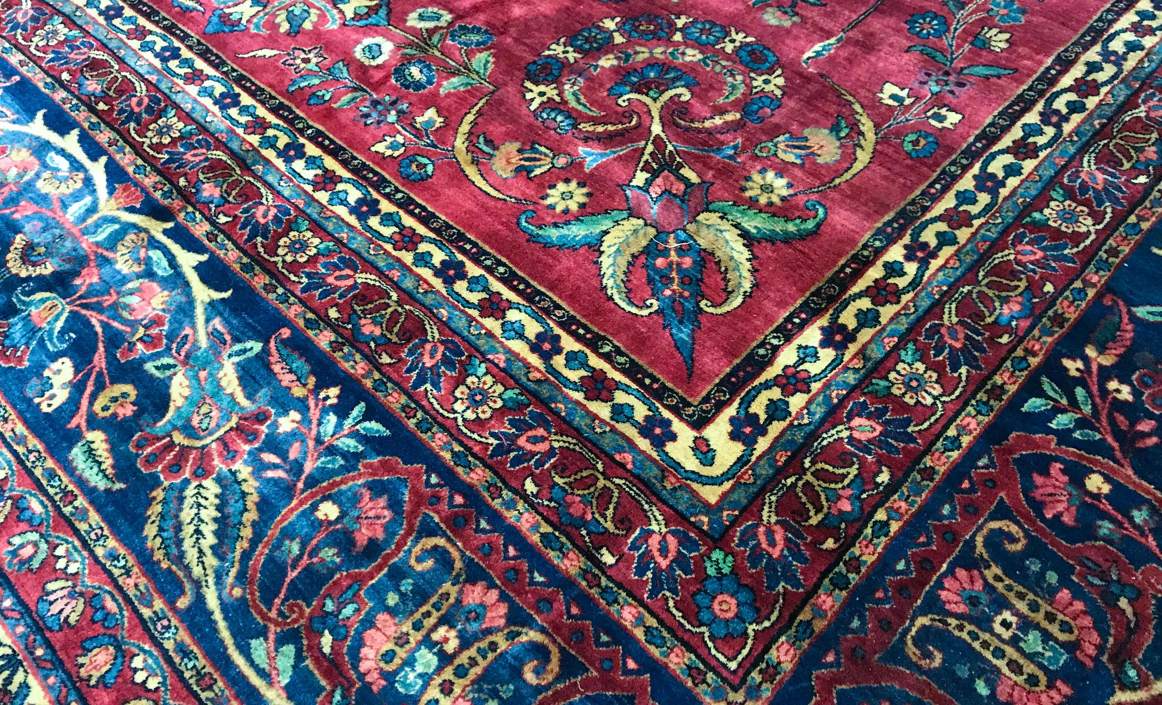 Vintage Persian Kerman oversize rug, circa 1940. This truly oversize rug has wonderful detail in the design, on the red ground the flowers in a variety of styles and shapes is complimented by the navy border continuing the floral theme and the