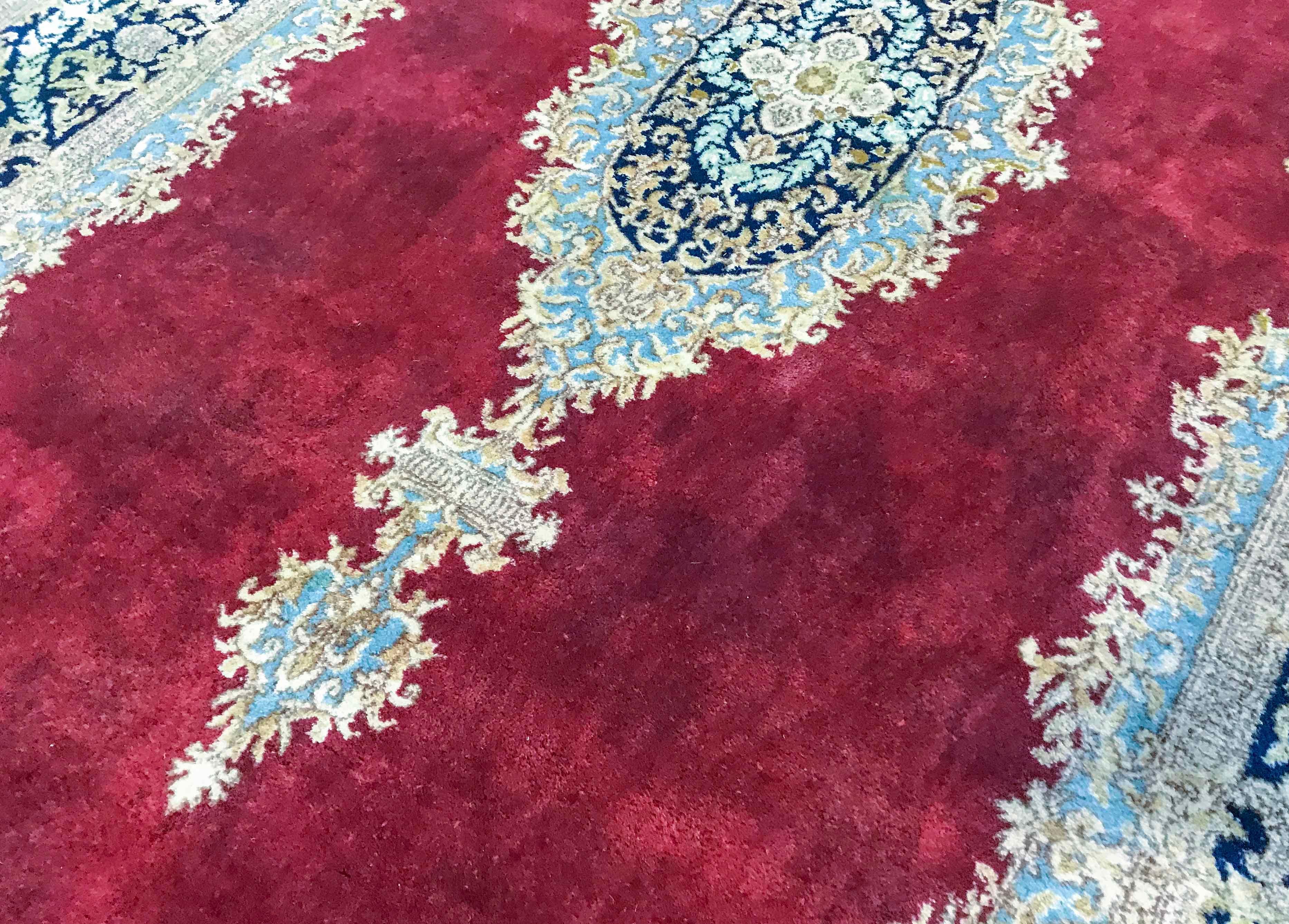Alter persischer Kerman-Teppich, um 1940. Ein beeindruckender, schmaler Teppich mit einem wunderschönen, tiefroten Feld und einem hellen Medaillon, dessen Farbgebung sich an den Seiten und in der Bordüre wiederholt, um einen Teppich zu schaffen, der