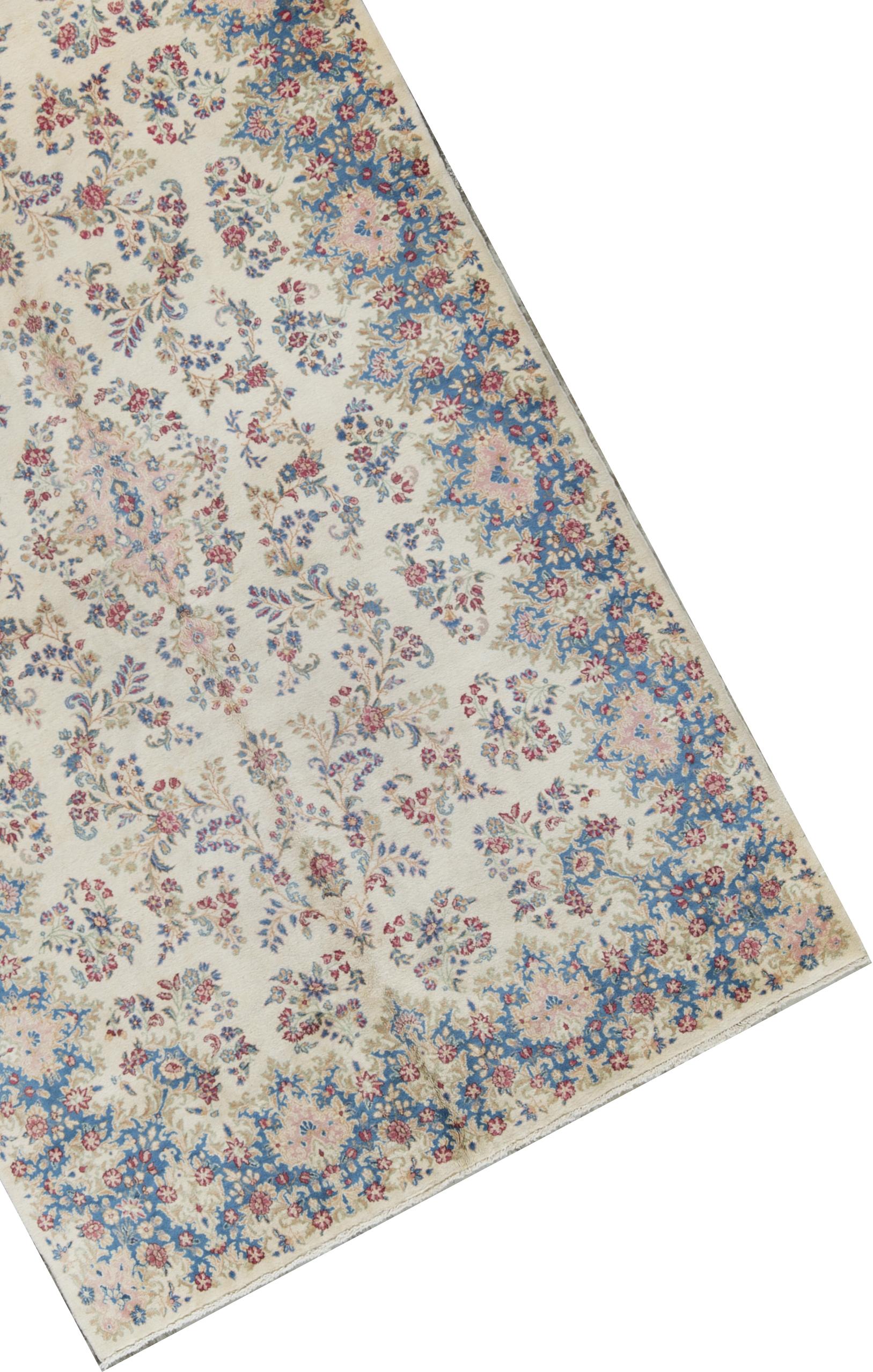Vintage Persian Kerman rug, circa 1940. A vintage 1940s Kerman rug with an all-over design, the main ivory field with floral and vine designs encompassing the whole rug enclosed by an attractive border in the same style but incorporating a soft blue