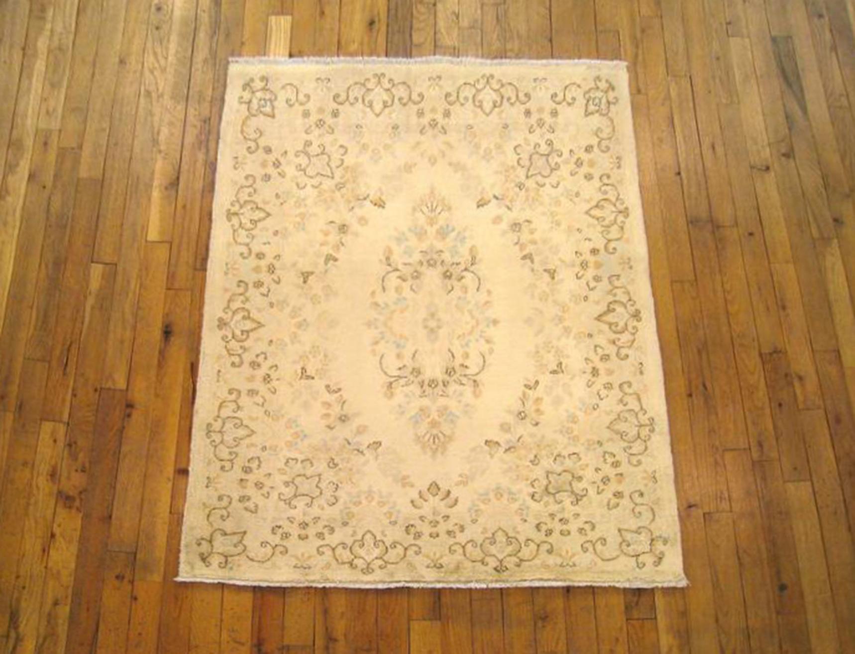 A vintage Persian Kerman rug from Persian Gallery New York, size 4'0 x 3'2, circa 1940. This fine handwoven wool carpet features a lovely floral motif in the ivory central field, with diffuse central medallion and an uncluttered border, making for