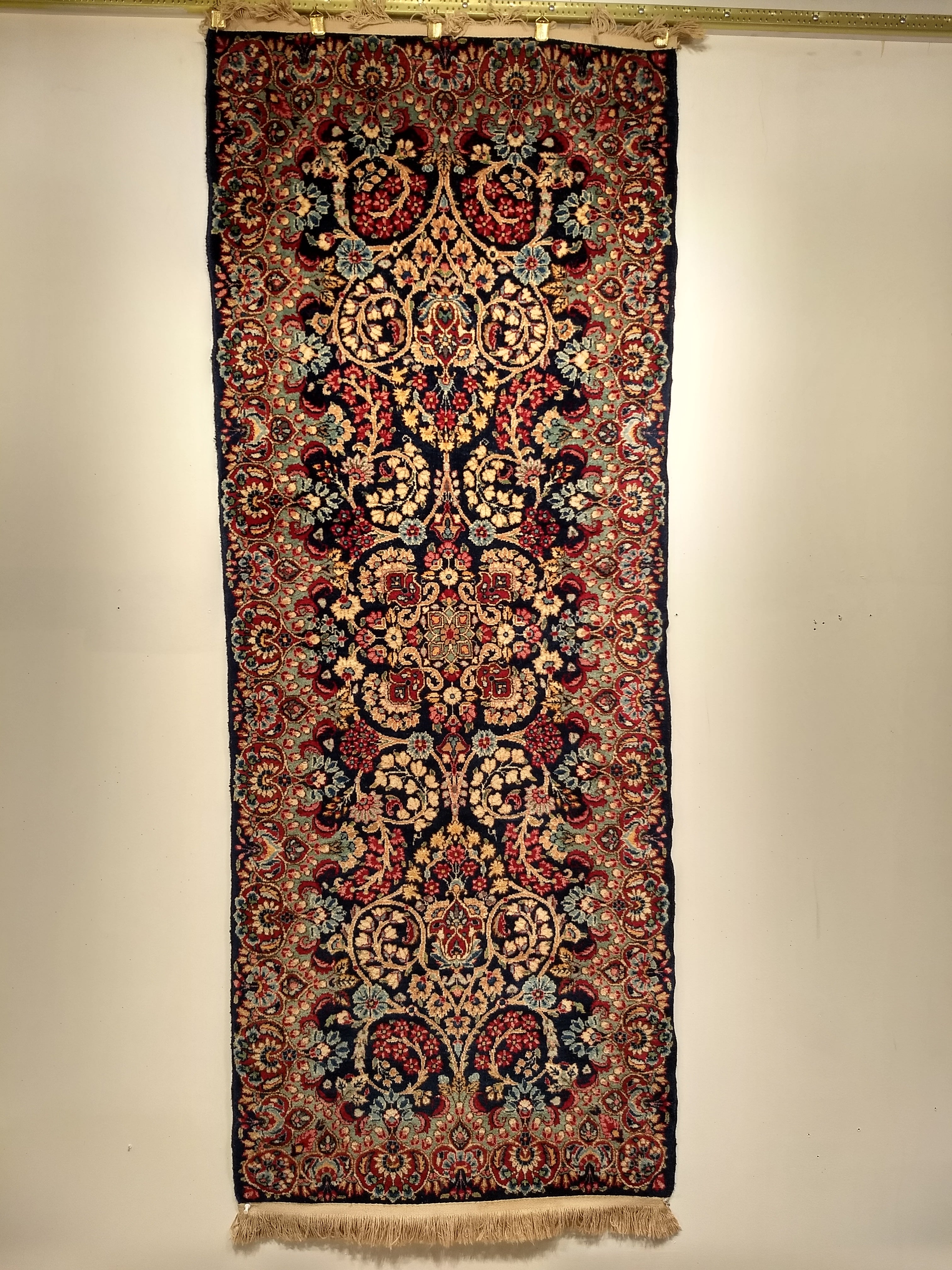 Ein schöner persischer Kerman-Läufer oder -Teppich mit einem floralen Muster aus den frühen 1900er Jahren.  Der Teppich hat eine marineblaue Feldfarbe mit floralen Mustern in Grün, Babyblau, Elfenbein und Rot.
Abmessungen:  2′ 6″ x 6′ 6″
Datum der