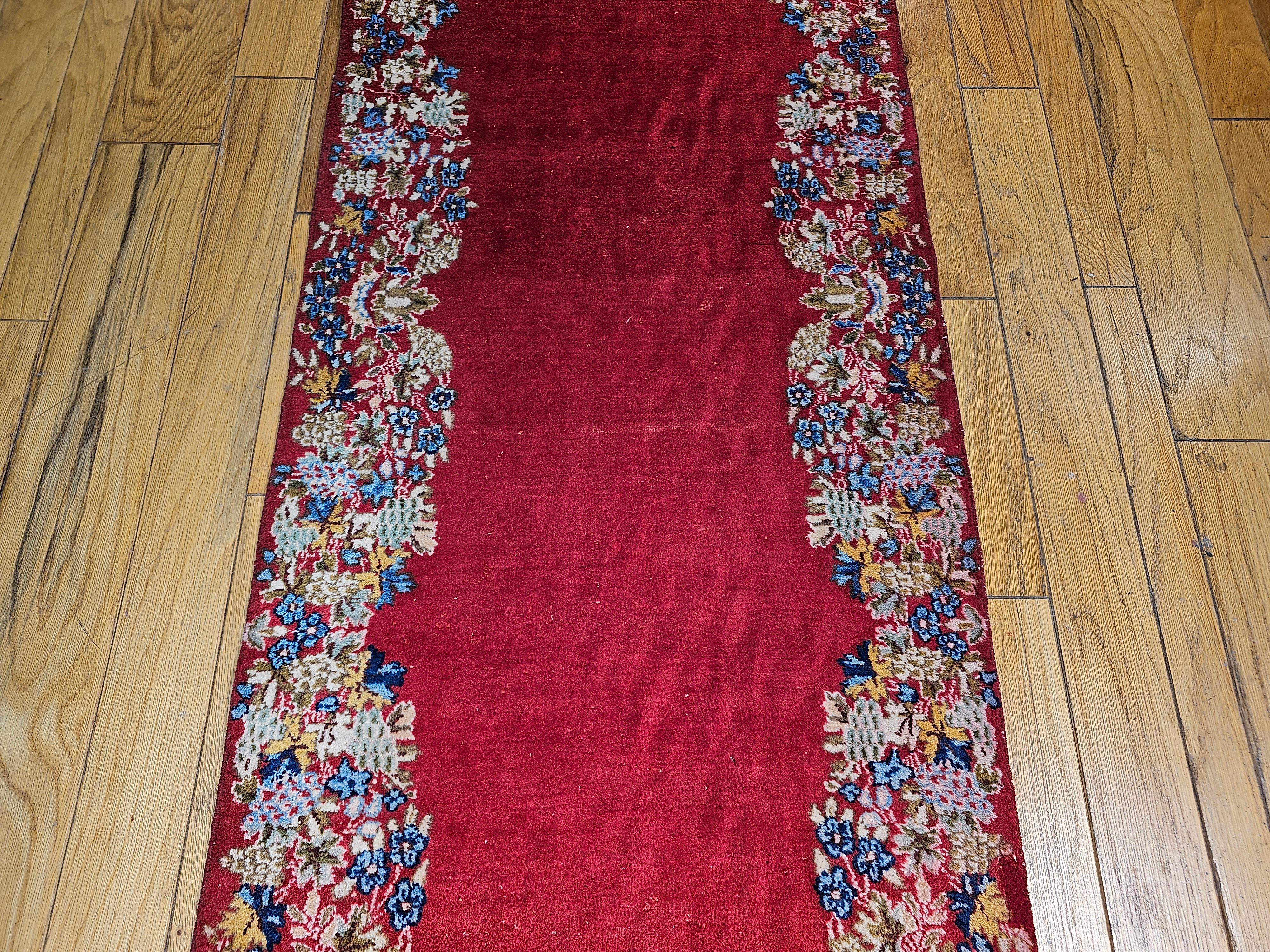 Annodato a mano Runner persiano vintage di Kerman con motivo floreale in campo aperto in rosso, blu e verde in vendita