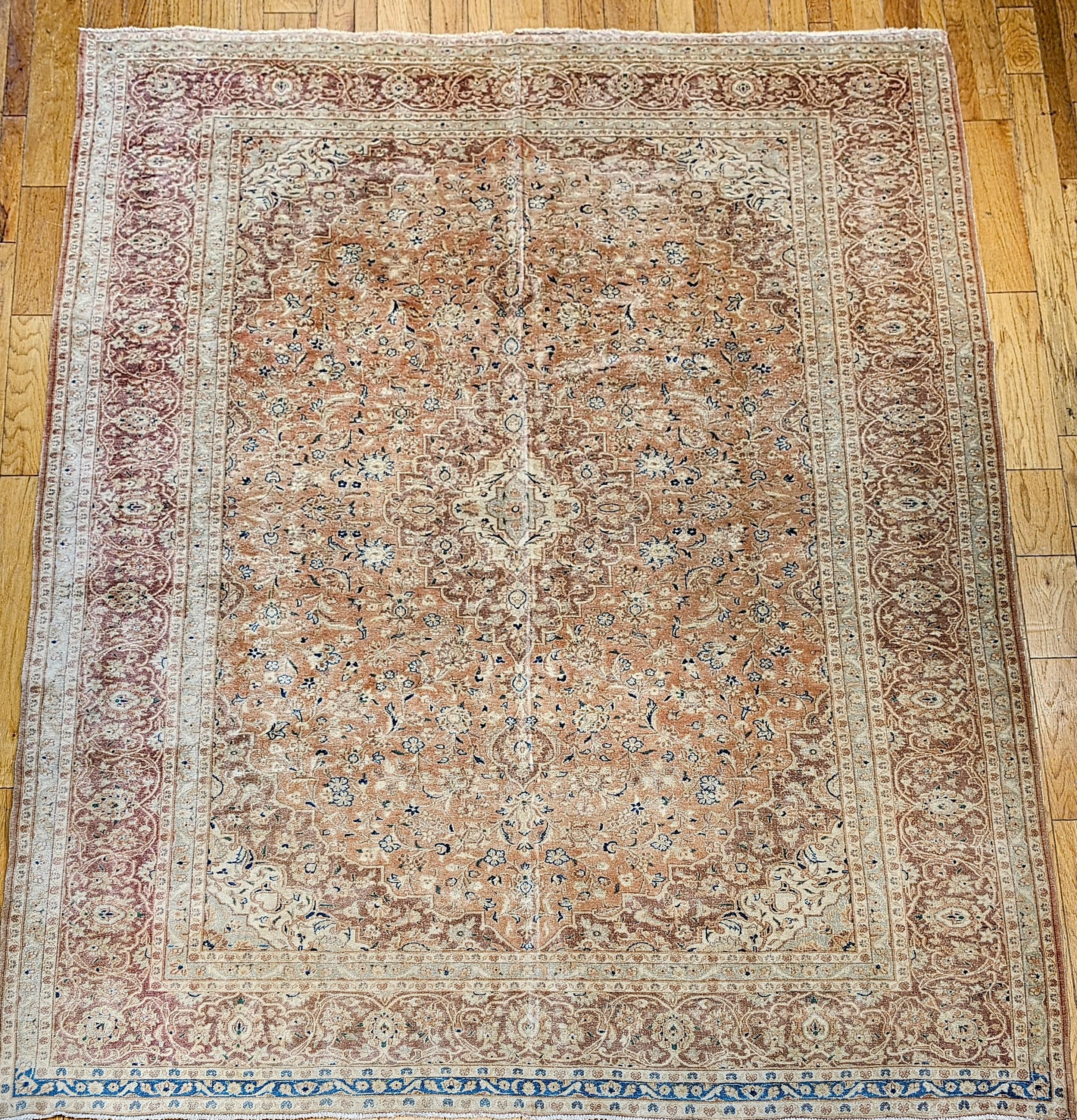 Wonderful example of a vintage Persian Tabriz room size rug in pale apricot color background with accent colors in green and blue from the early 1900s.  The rug is in an allover pattern with a small central medallion and the corner spandrels in