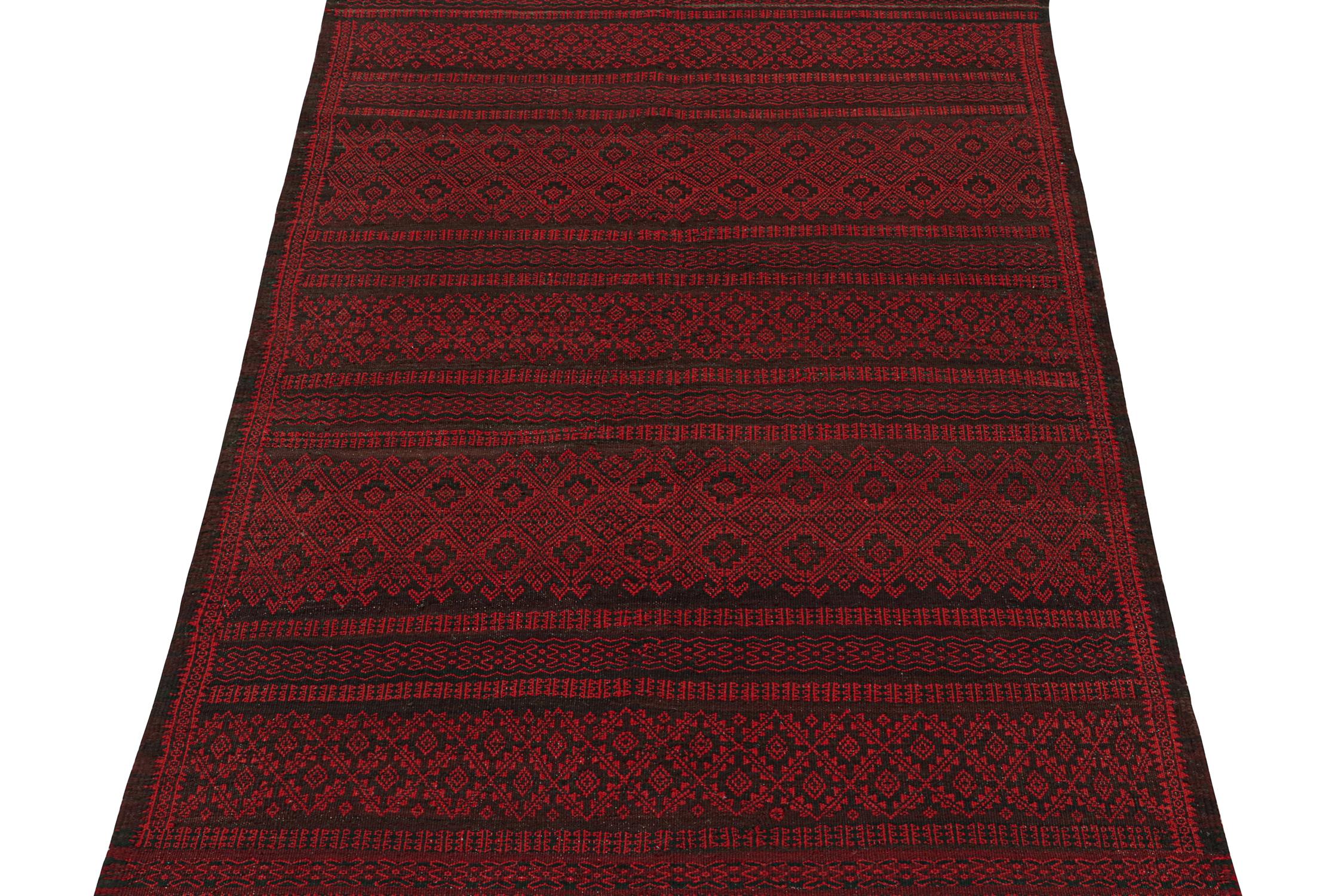 This vintage 5x7 kilim is a midcentury tribal rug that originates from Turkey—handwoven in wool, circa 1950-1960.

Its design enjoys a rich play of burgundy with crimson red and black geometric patterns. 
This midcentury tribal Kilim further