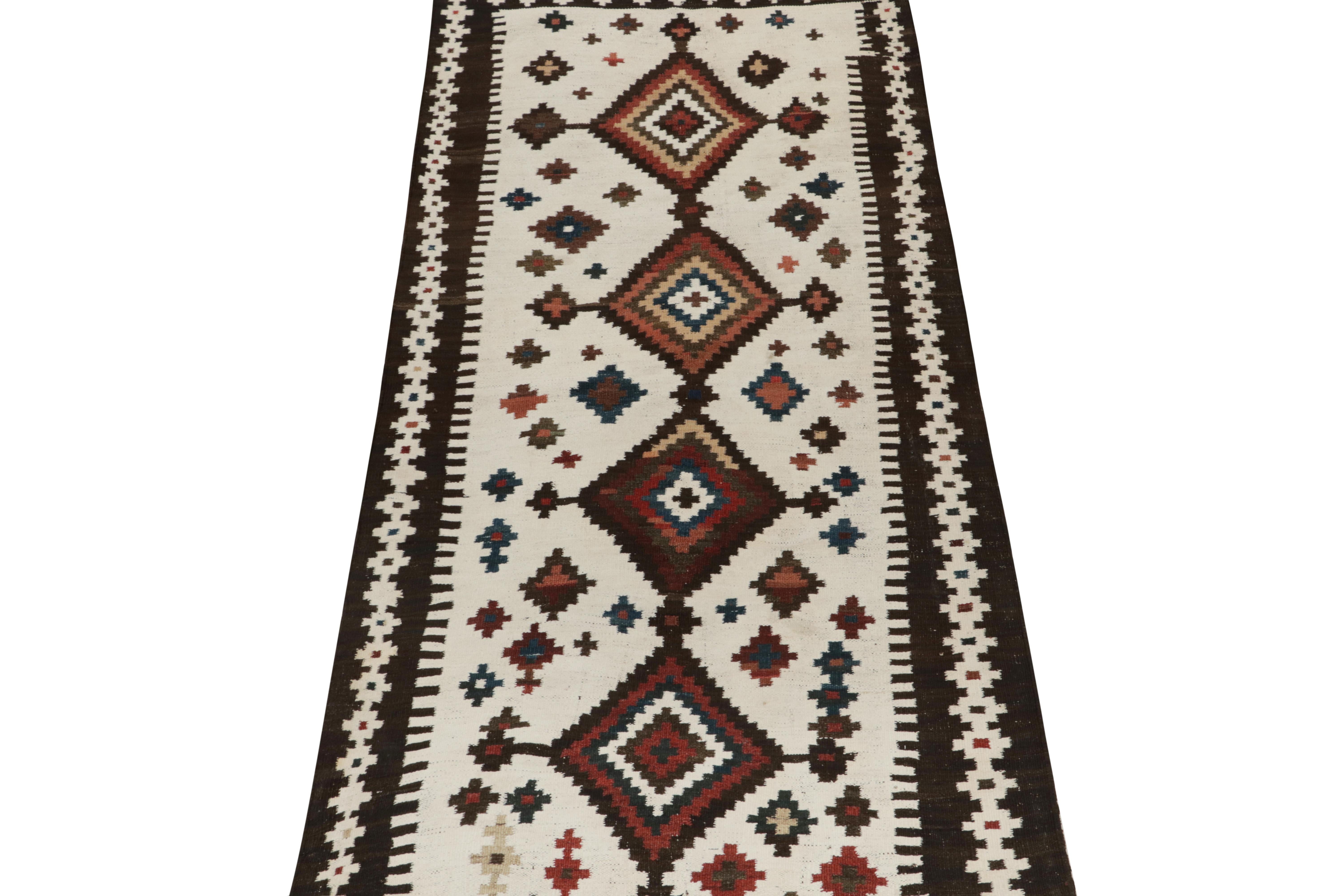 This vintage 4x7 Persian kilim is a unique tribal rug for its period, handwoven in wool circa 1950-1960.

Further on the Design:

A white open field hosts repeated medallions with an emphasis on rich brown, rust red, and blue accents.