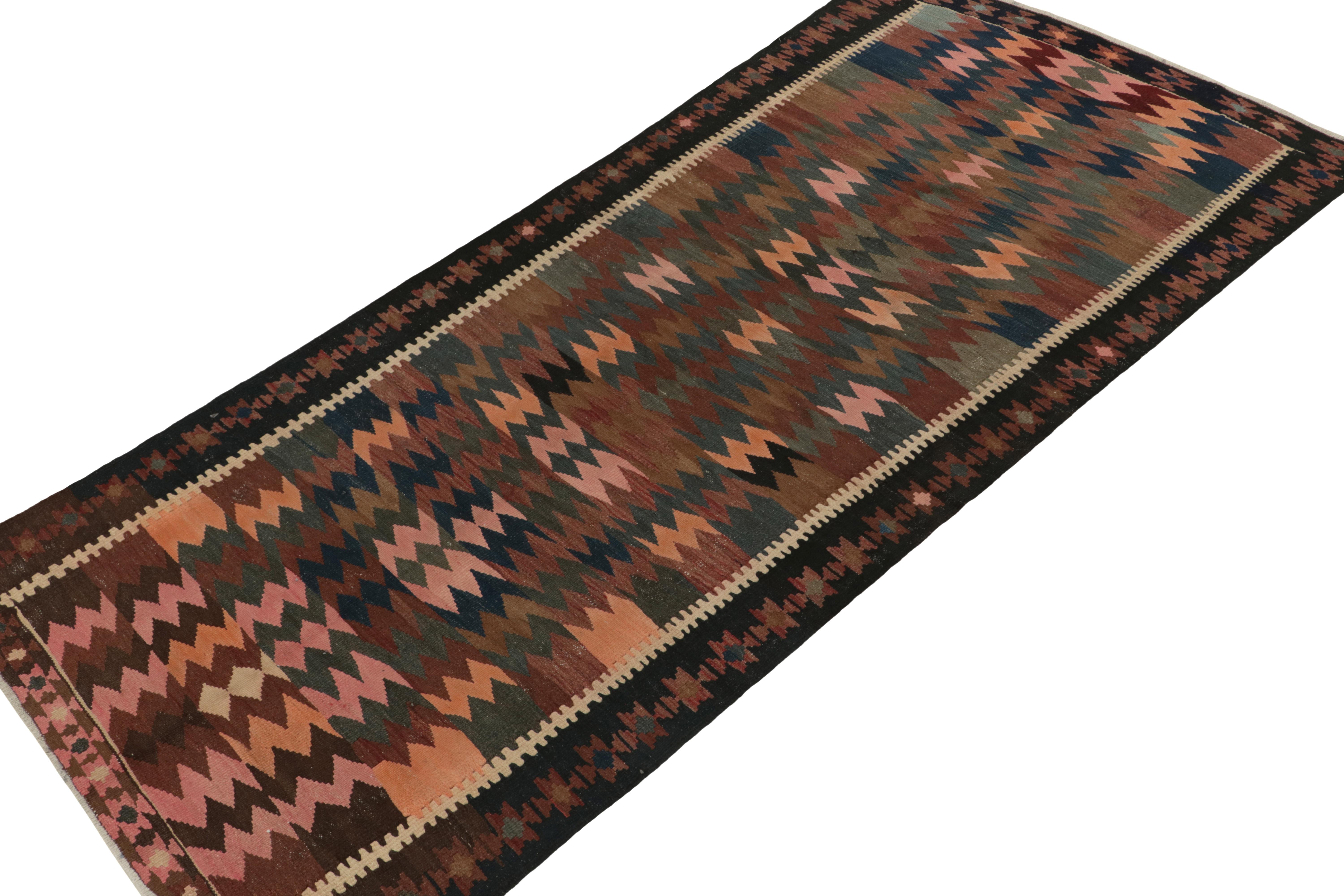 Handwoven in fine wool, a 5x10 vintage Persian kilim originating circa 1950-1960. An intriguing piece from the mid-century, the gracious scale reflects a playful colorway in pink, beige-brown, blue and green with an equally uncommon peach tone in
